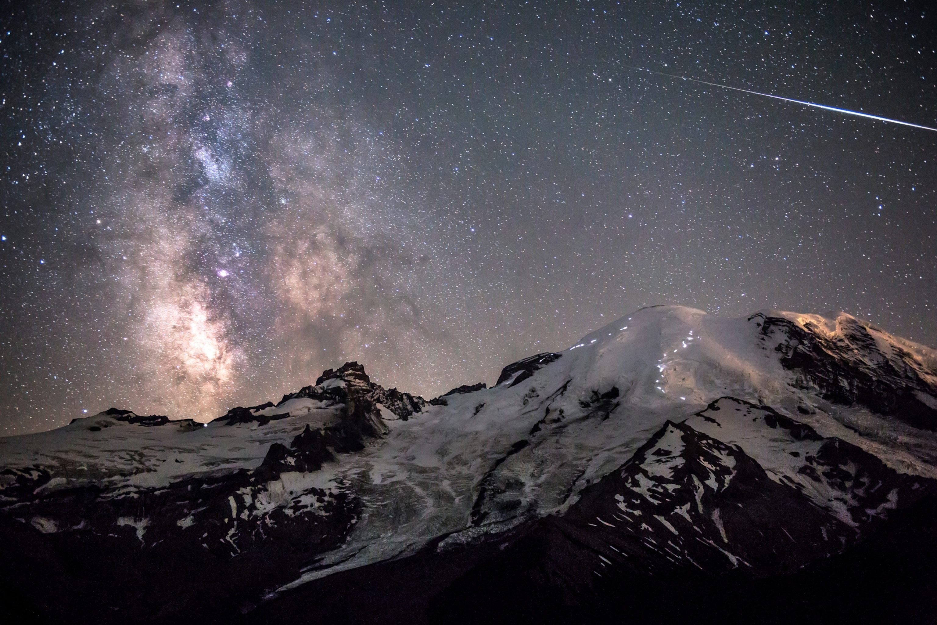 A bright Alpha Capricornid fireball over Mount Rainier with the Milky Way in the background. You can also see the headlamps of climbers making their way up the mountain, which adds a nice sense of scale and helps tell the story of a busy summer night on the mountain.