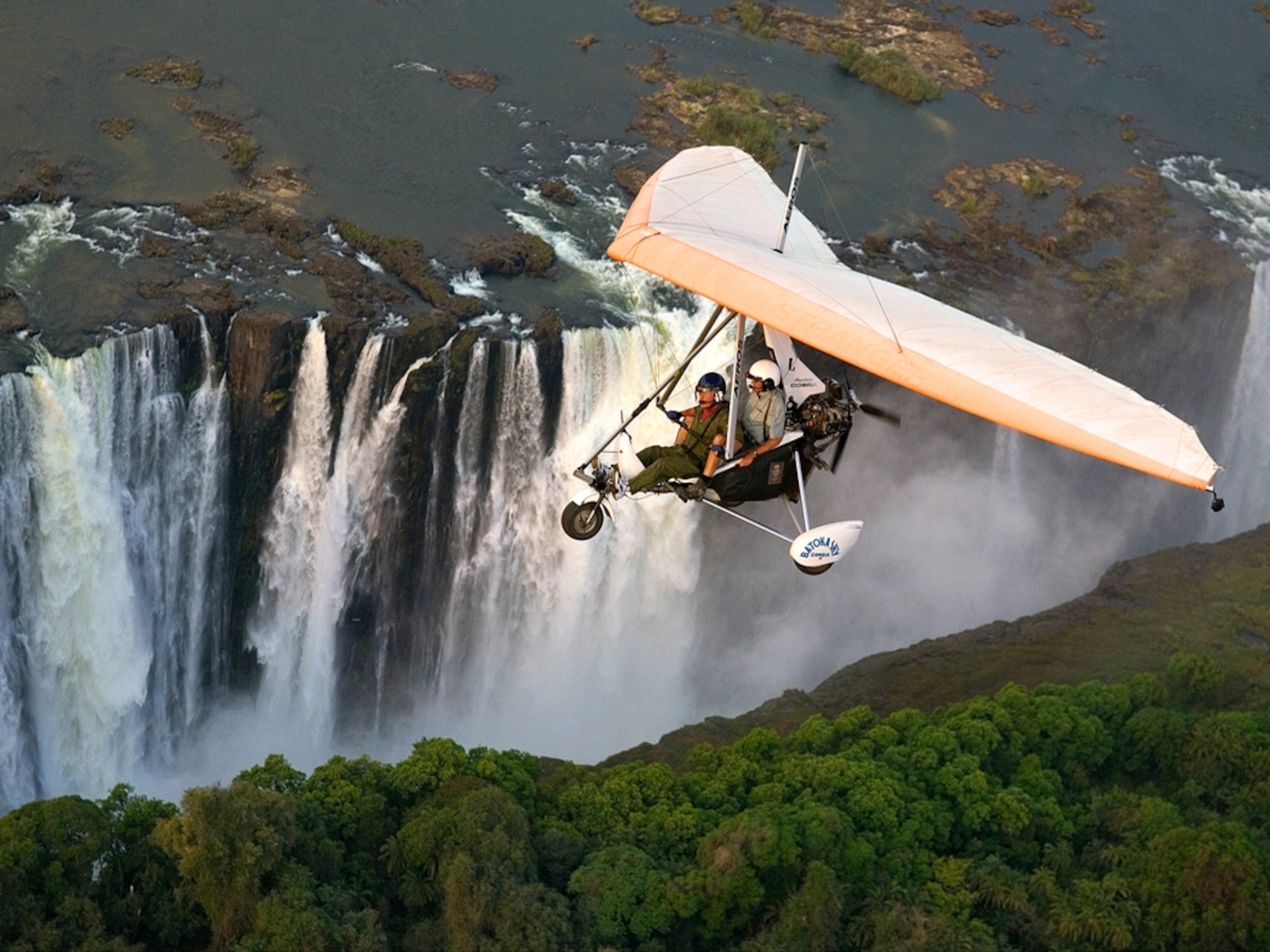 Microlight plane flying over waterfall