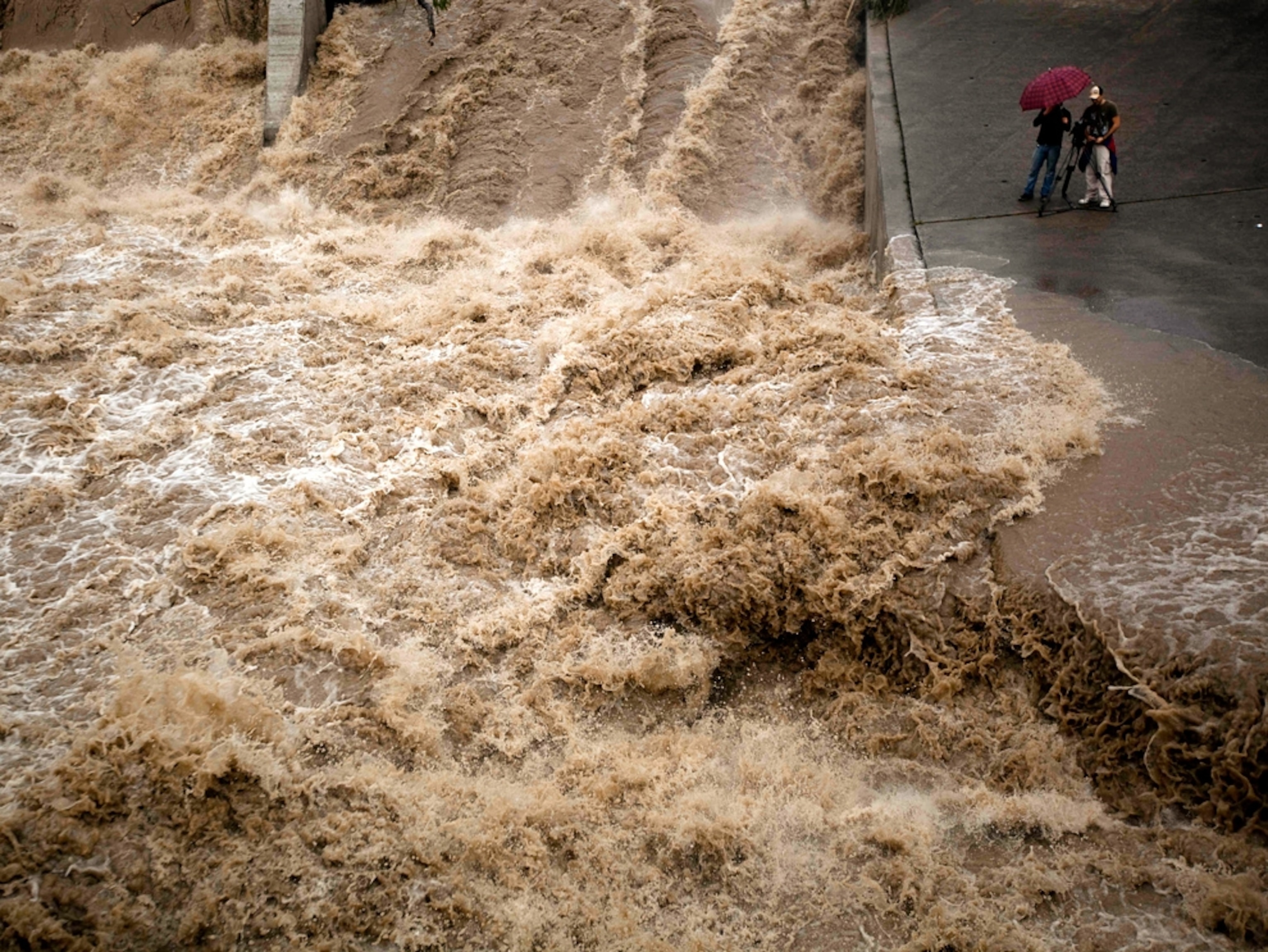 muddy flood waters spilling over a dam in Guatemala