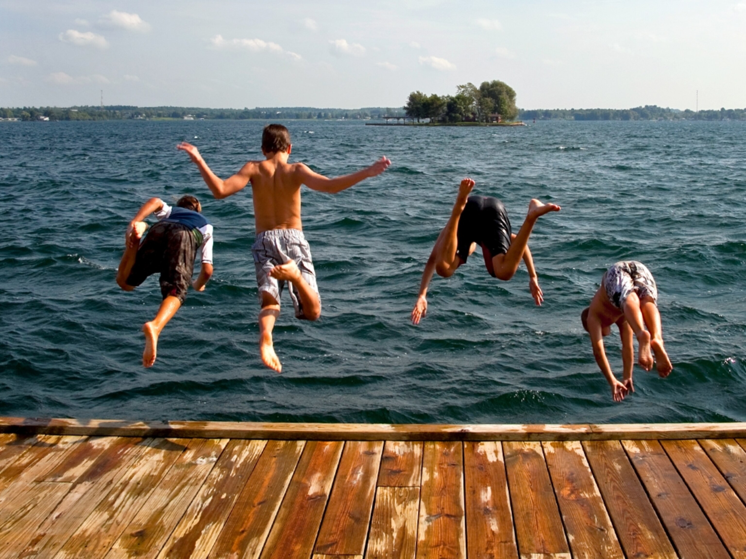 Boys jumping off dock into water