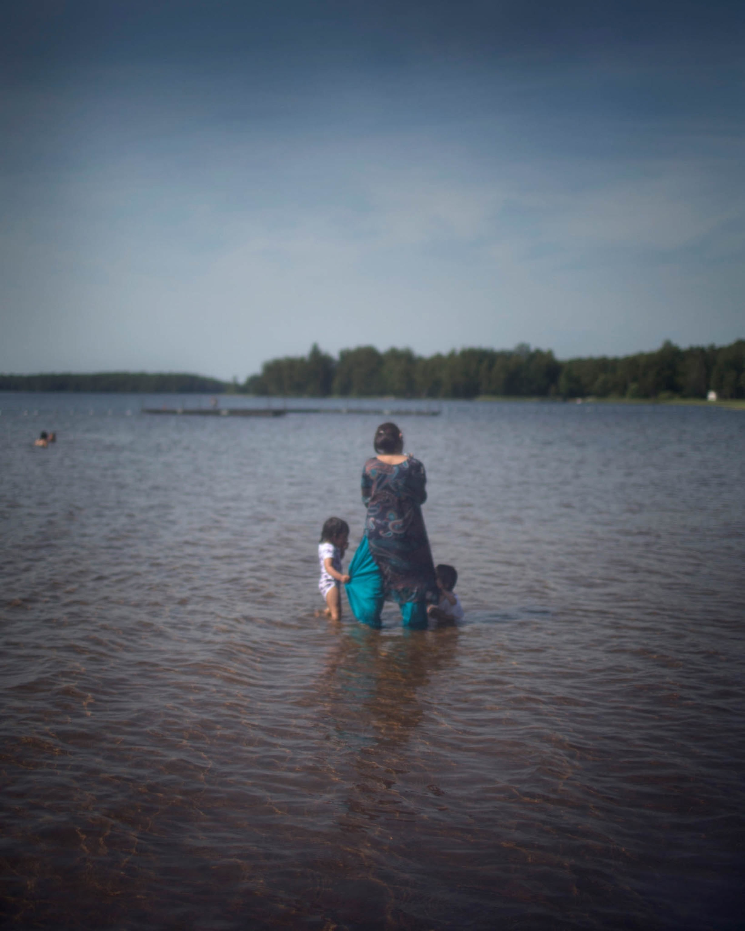 women and children wading in lake