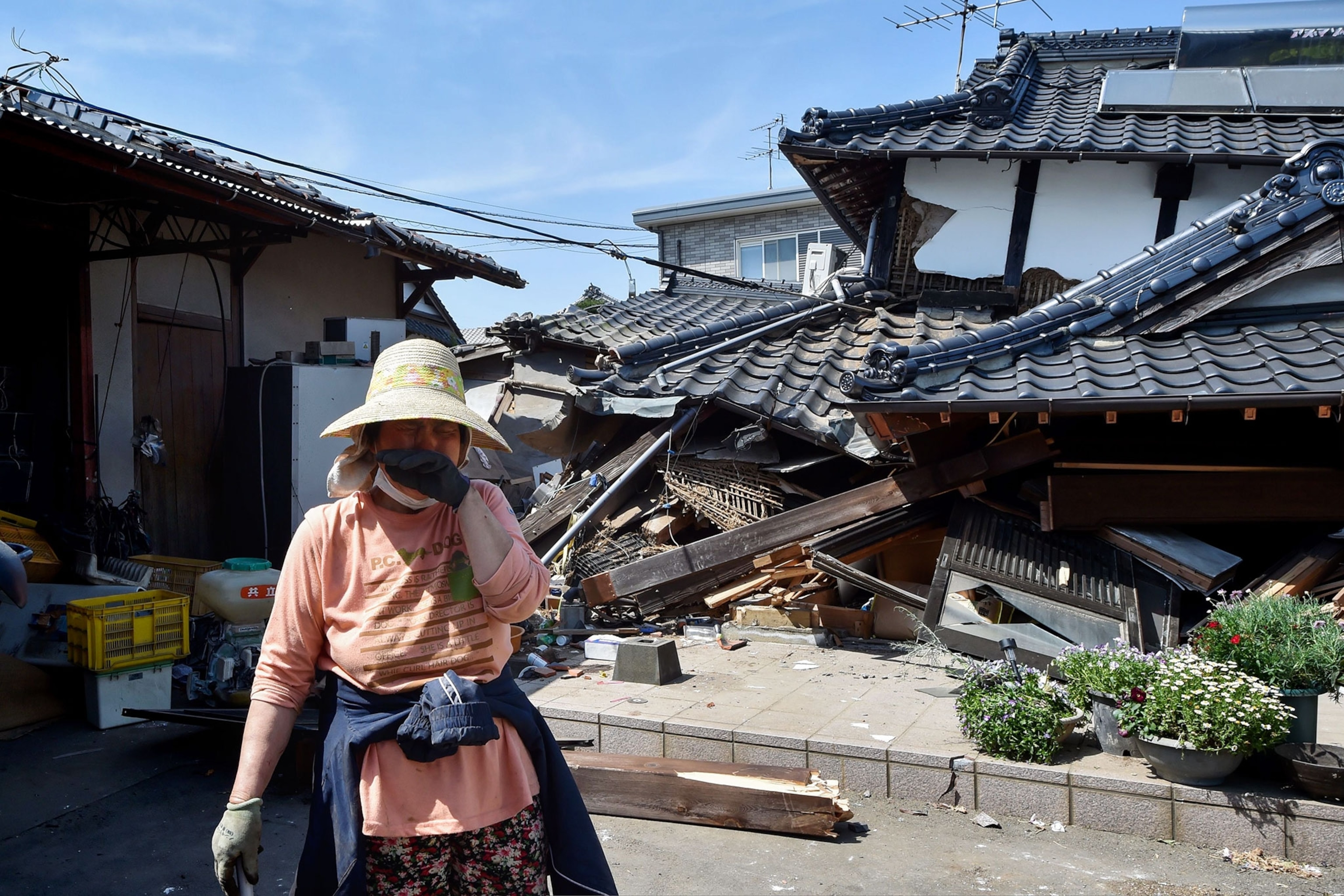 a woman standing outside her home destroyed by an earthquake