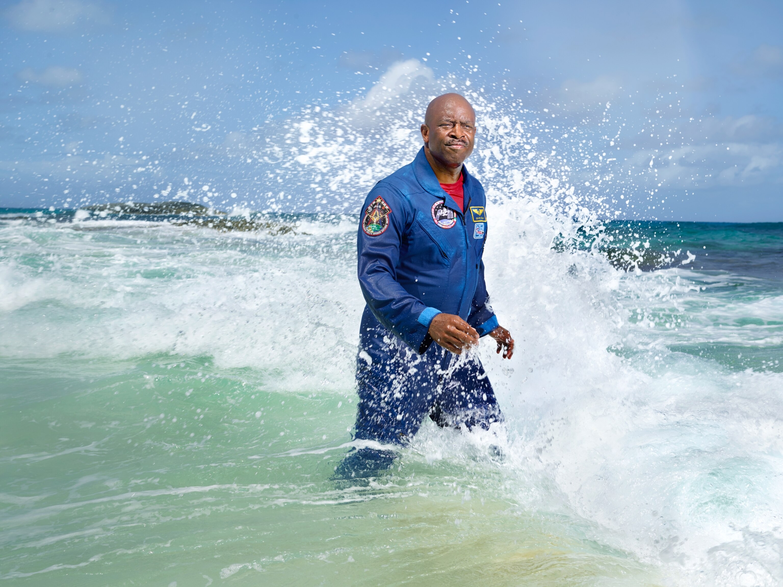 Leland Melvin walking out of the ocean with waves hitting against him