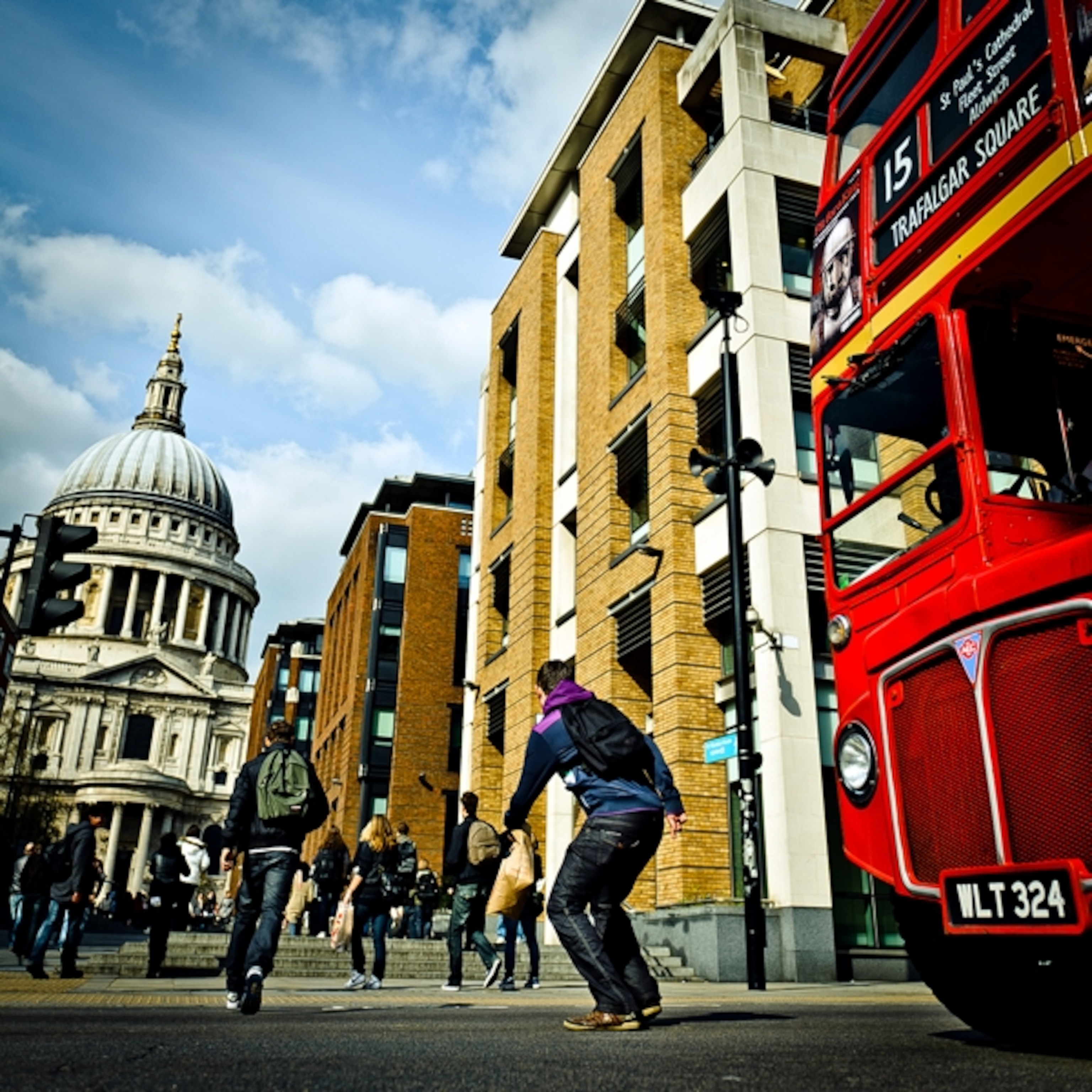 a man jumping from a red bus to a city street
