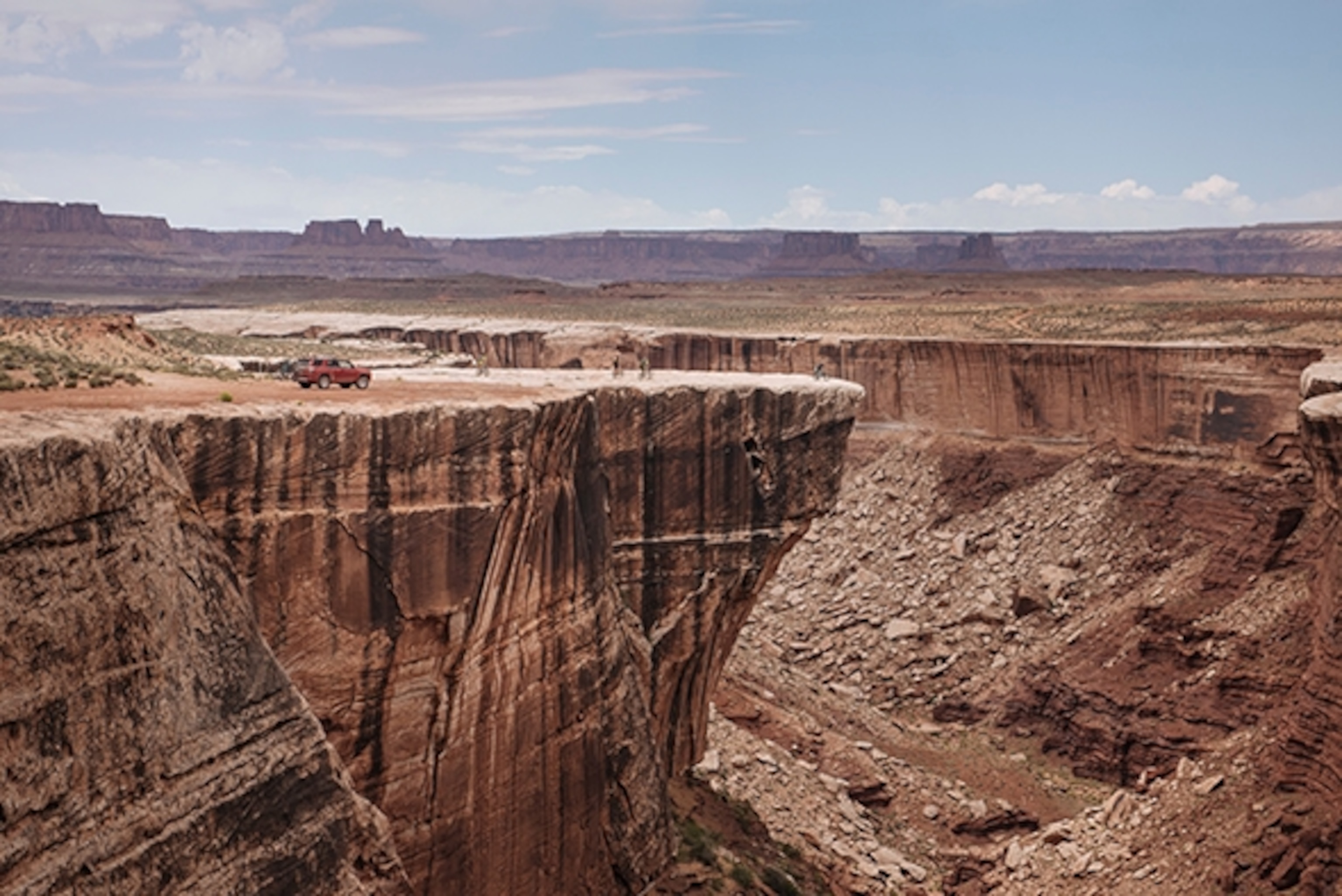 Our UT by Dirt team stops at an overlooking, edging the massive cliffs that line the lower step in Canyon Lands National Park, Utah;  Photograph by Max Lowe