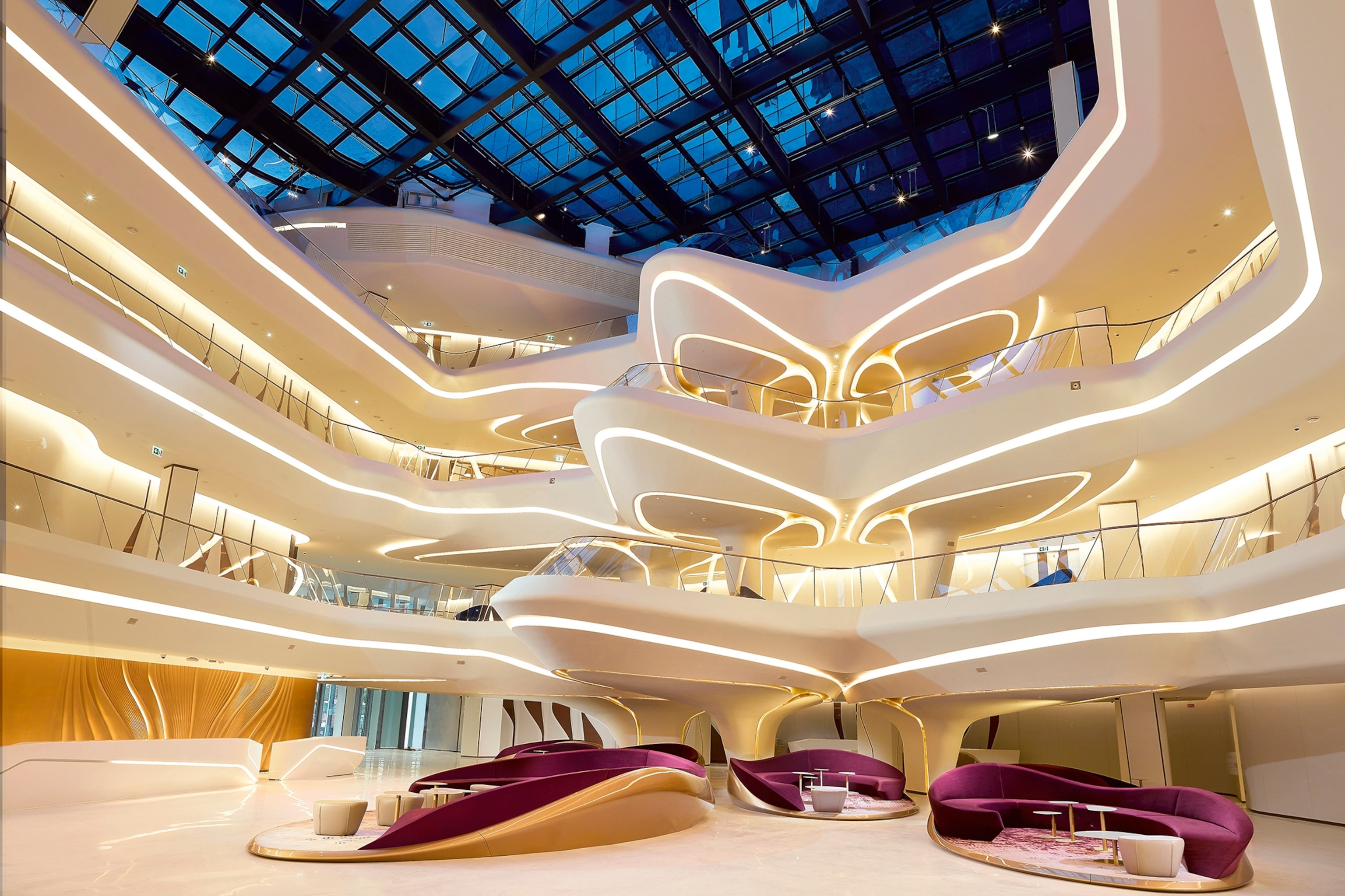 A spaceship-like, multi-level hotel lobby with smoothly curved balconies and light lines running along the edges.