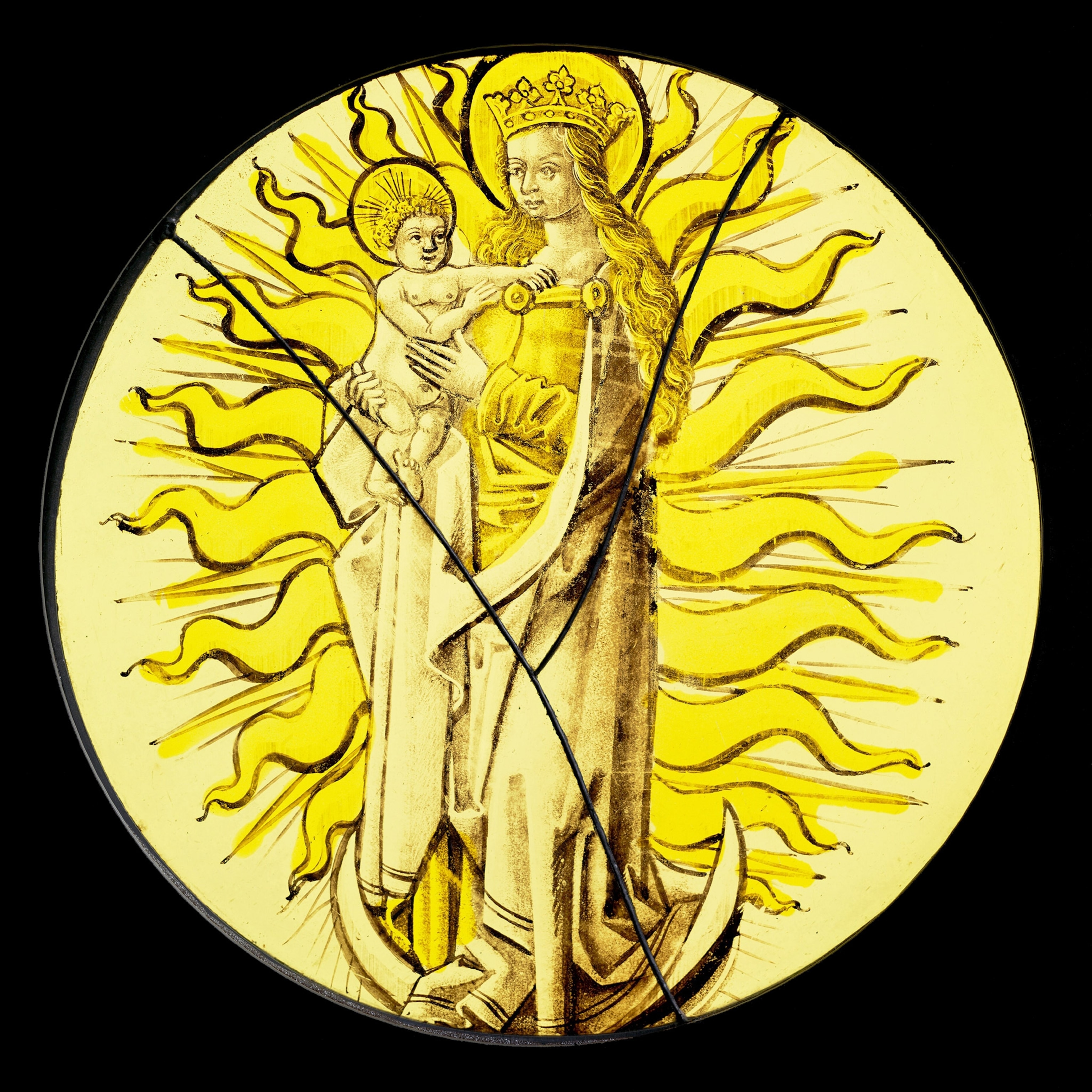 Against a square black background, a yellow stained glass circle bears a central figure of a woman wearing a crown and robes, long yellow hair, turned to her right and holding a baby in her arms, while squiggly rays of sunlight emanate out around them