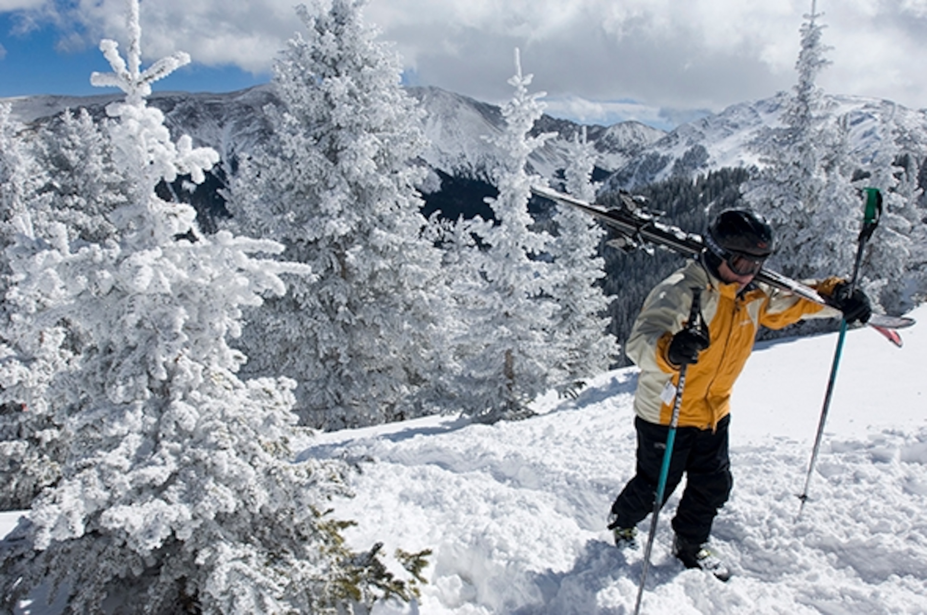 A skier from Santa Fe, New Mexico, hikes through snow-covered trees to the undeveloped ridge above Taos Ski Valley, Taos, New Mexico. Taos, one of the nations last family-owned ski resorts, is small and intimate, and features much expert terrain.