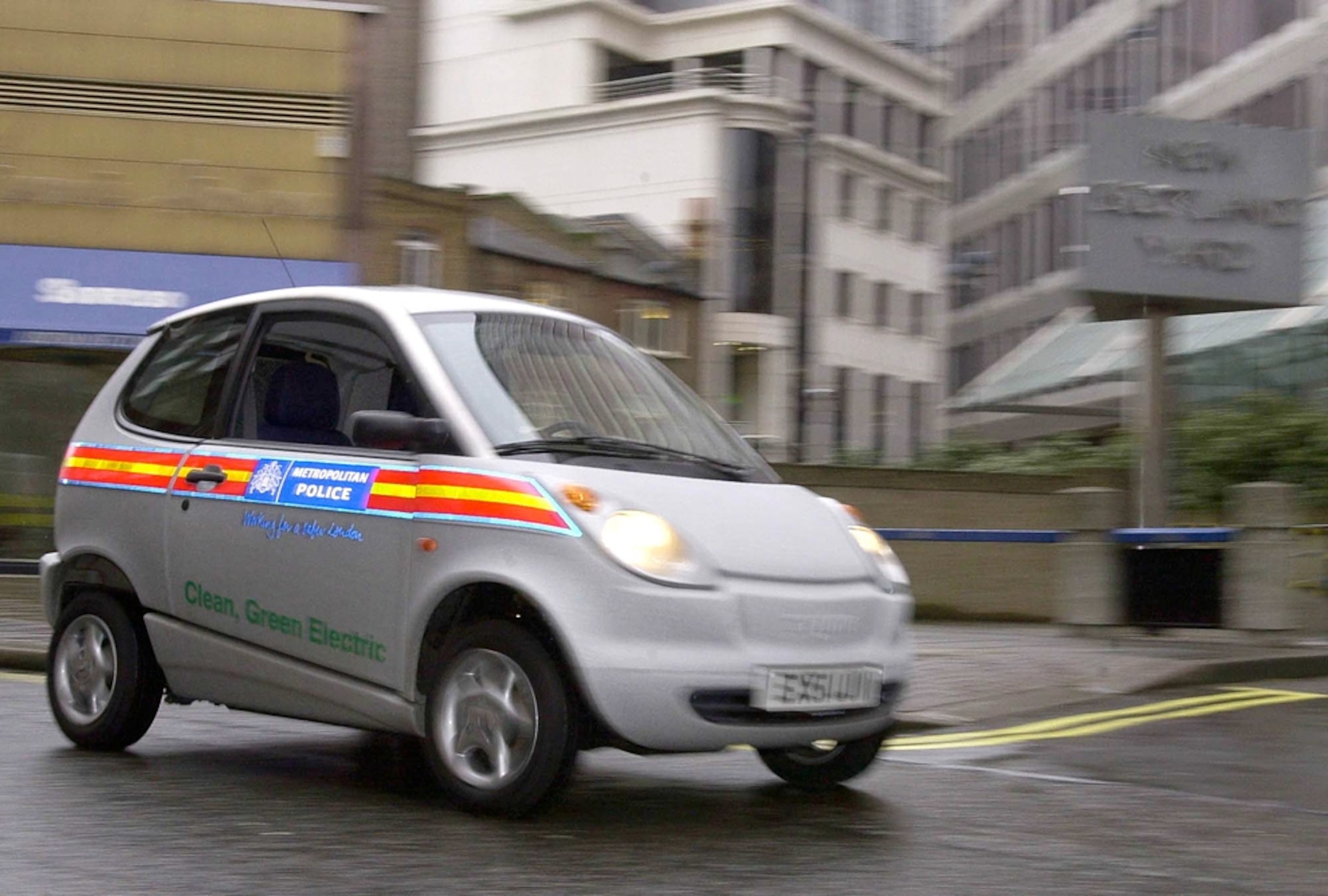 A Think City electric vehicle drives past New Scotland Yard in London