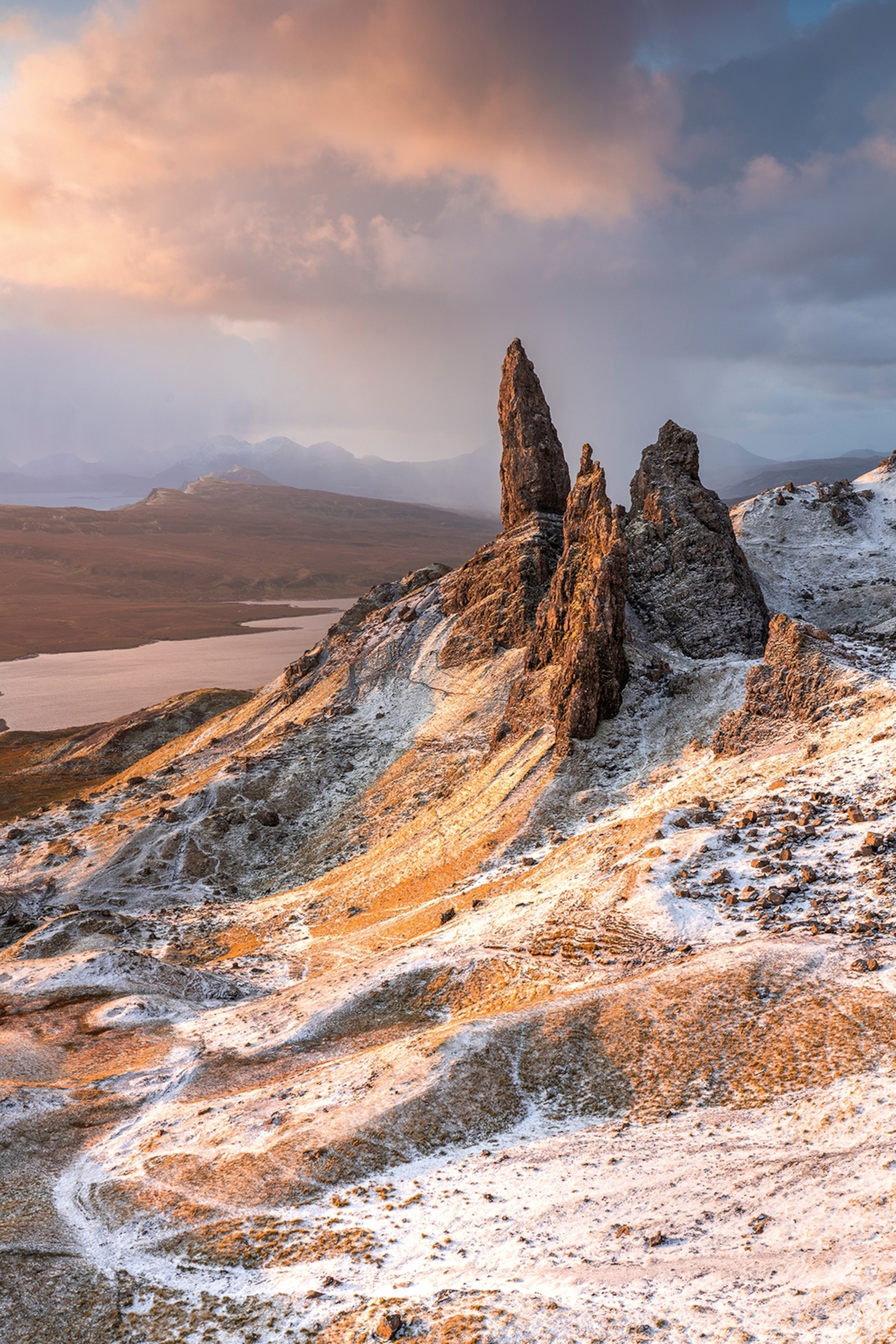 The tip of a rocky mountain with snow spreading sporadically across.