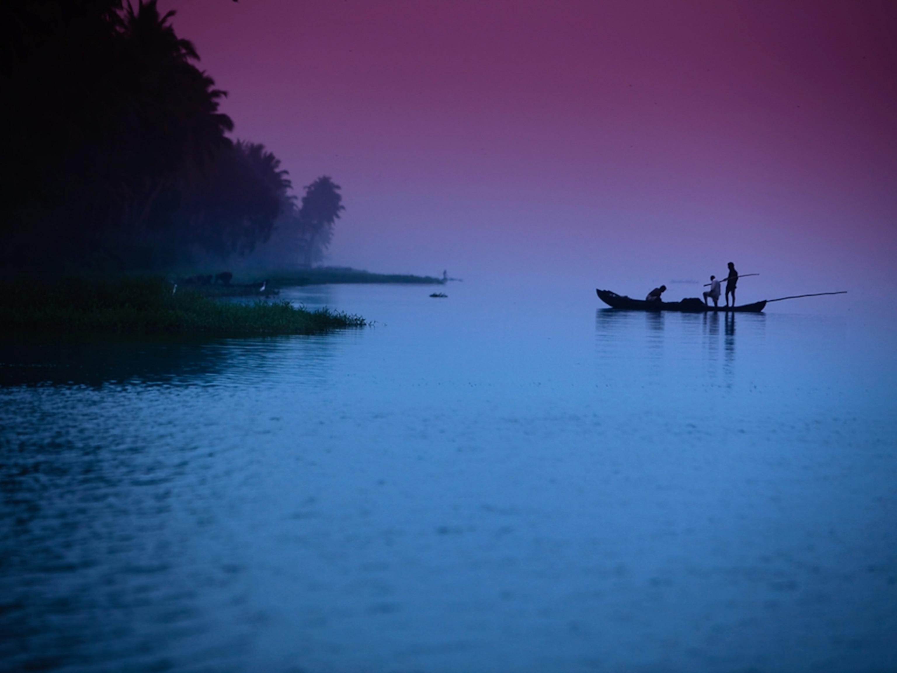 Fishermen in a boat on a lake before dawn