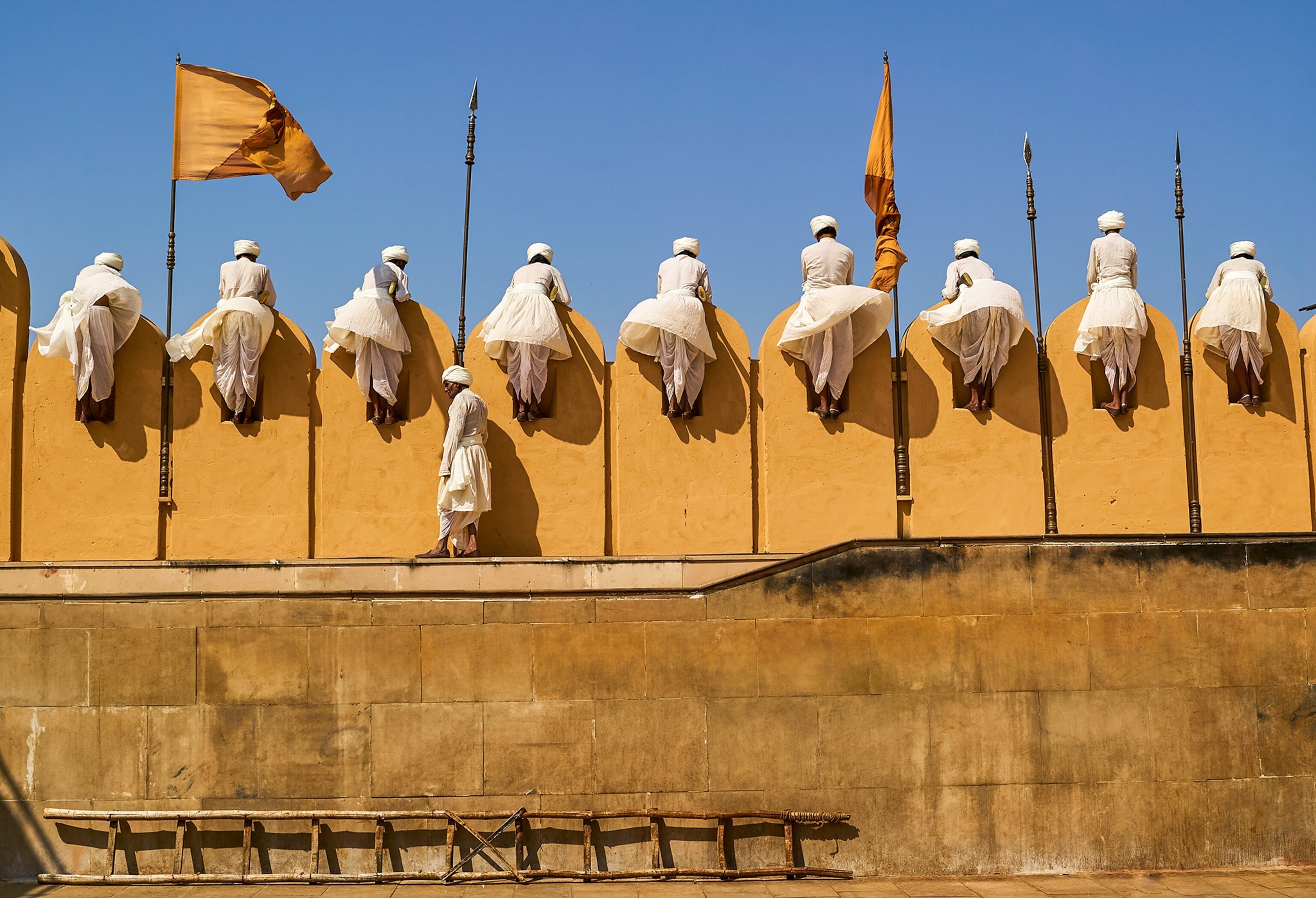 men peering over a wall at a ceremony in Rajasthan, India