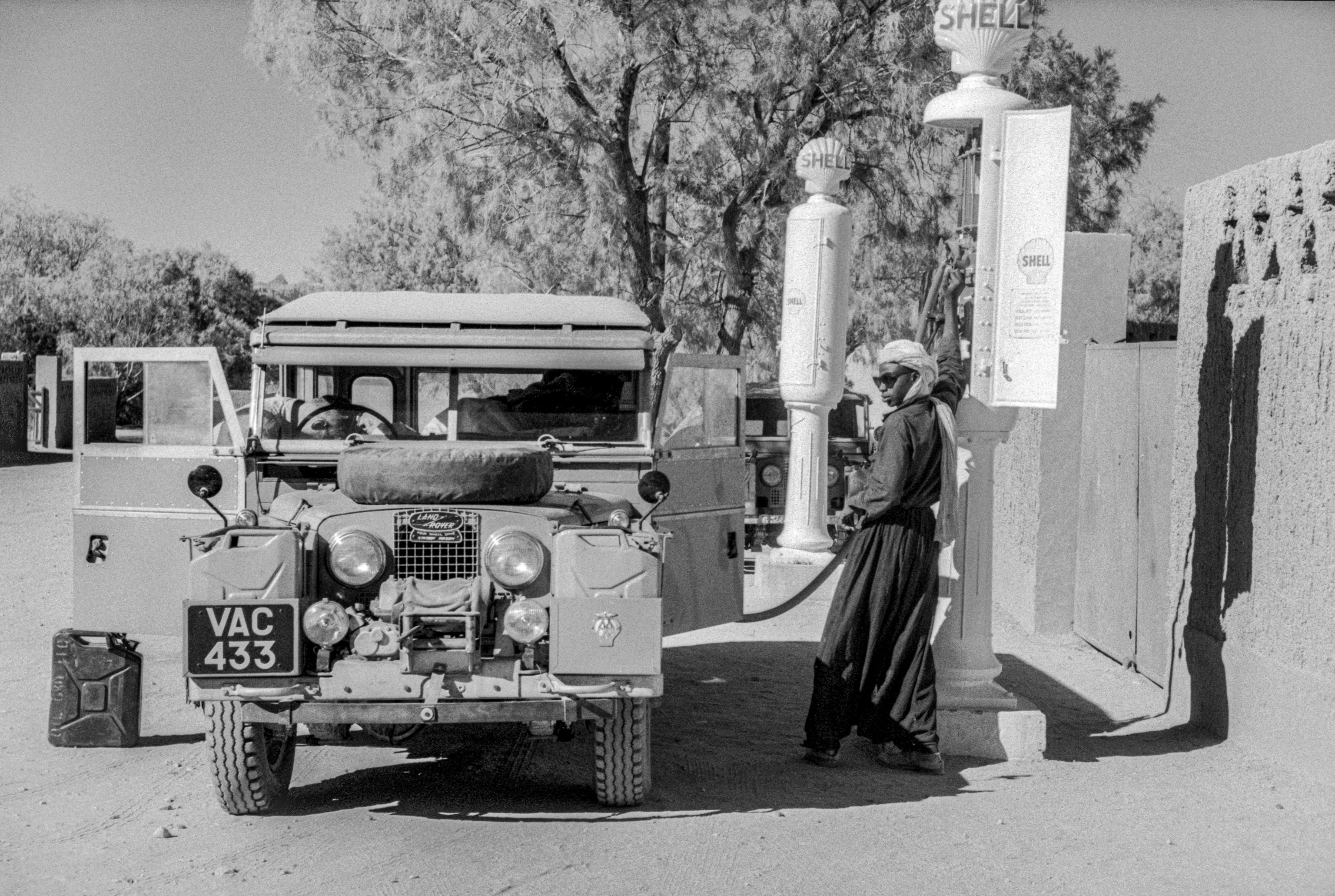 A man stands next to a car pumping up gas