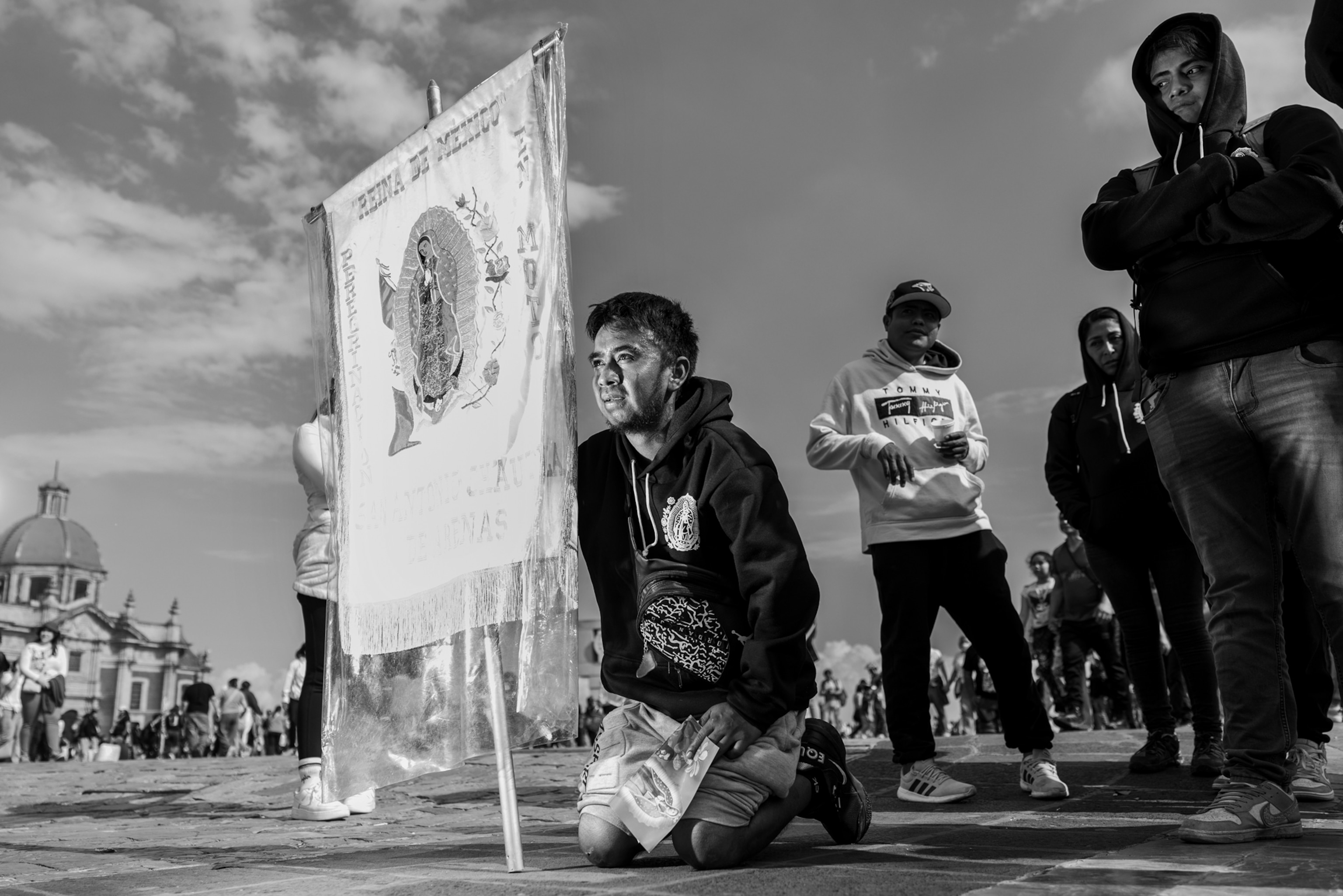 A person kneels on the ground with a flag