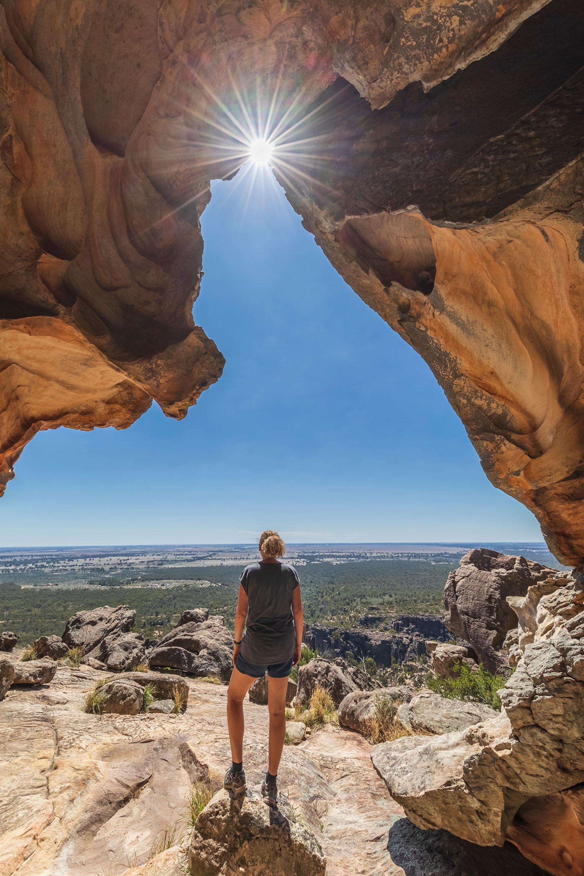 Australia, Victoria, Female tourist admiring surrounding landscape from entrance of Hollow Mountain cave in Grampians National Park.