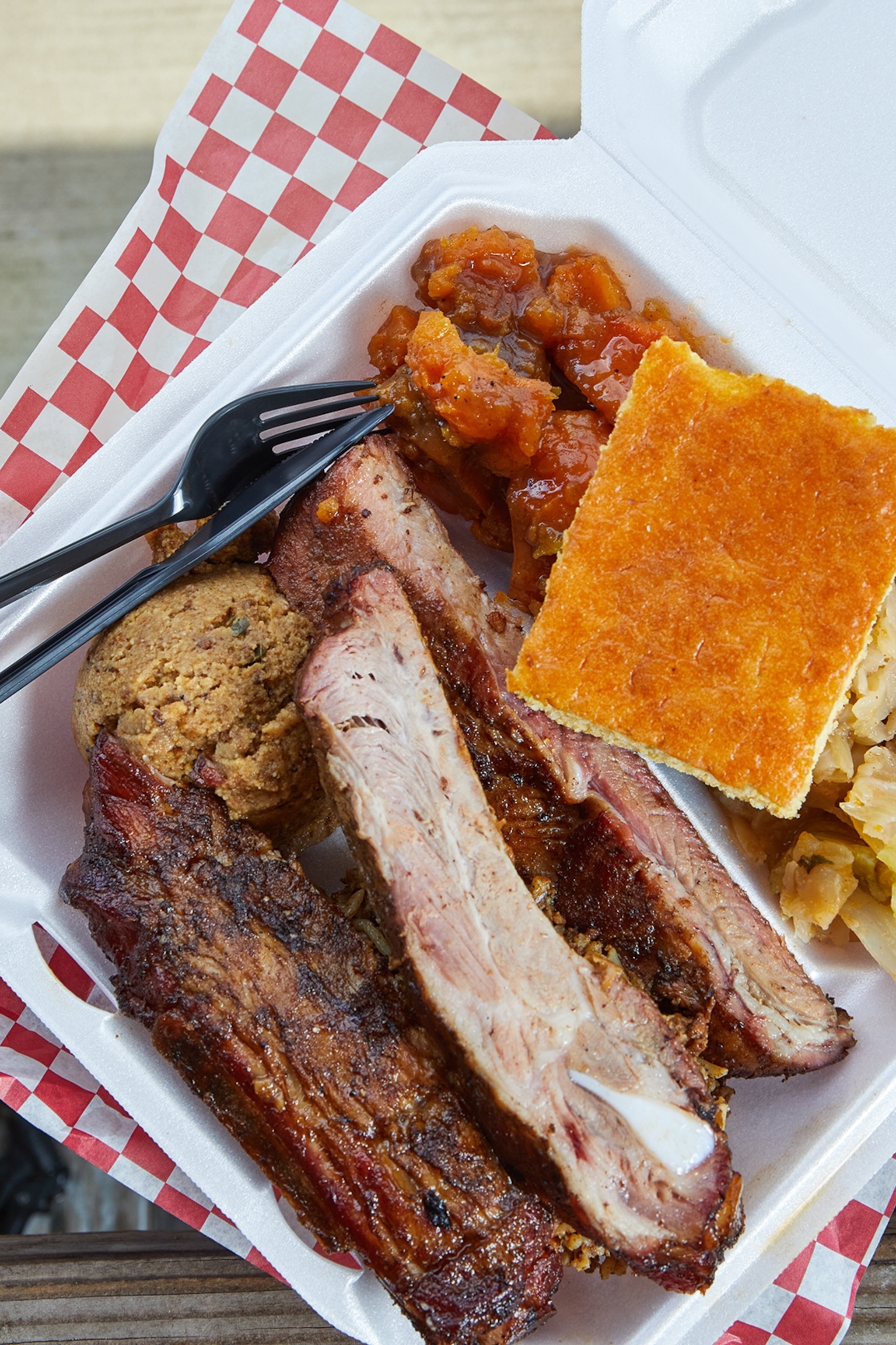 A styrobox with ribs and corn bread.