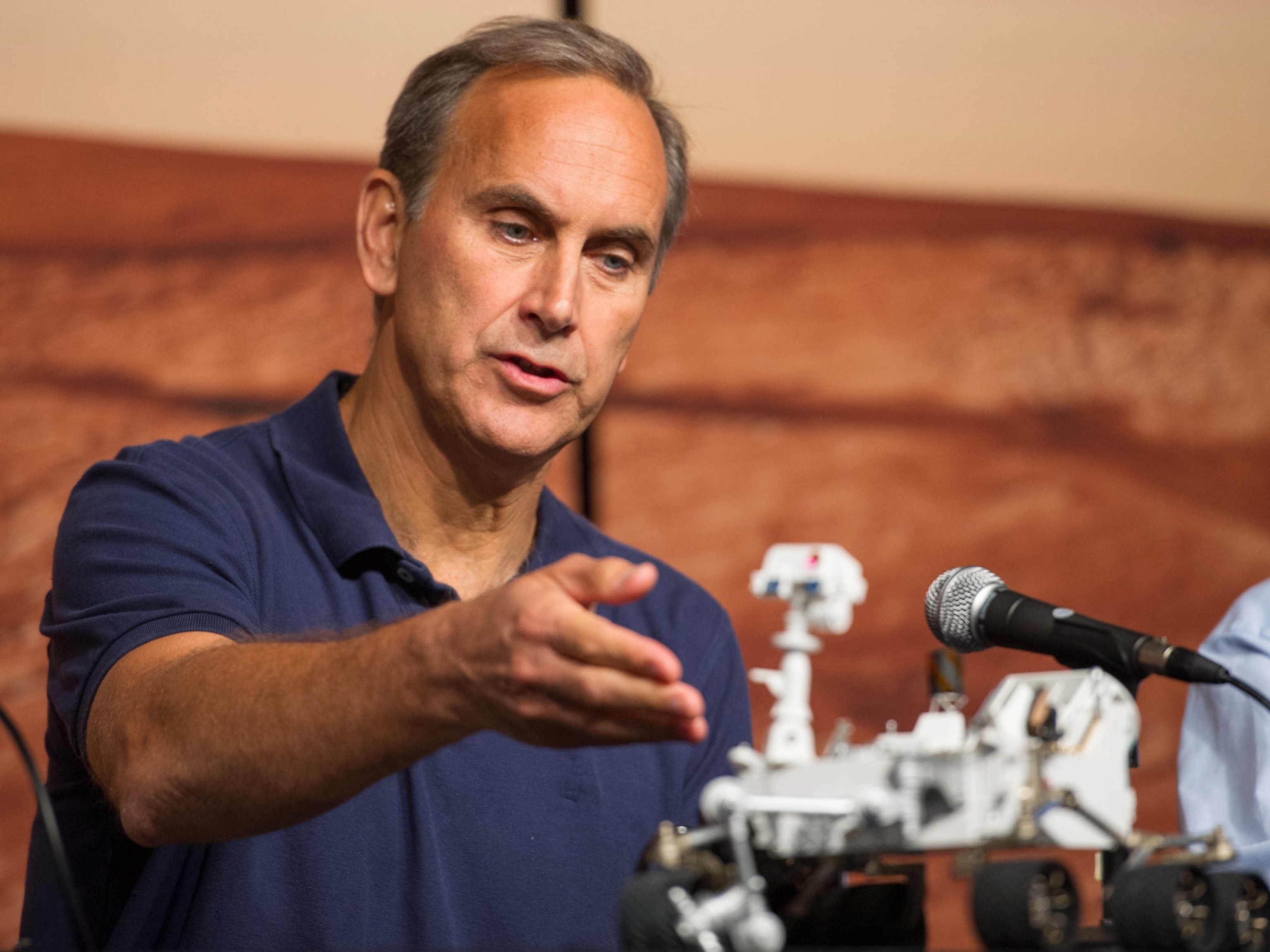 John Grotzinger points at a model of the Curiosity rover.