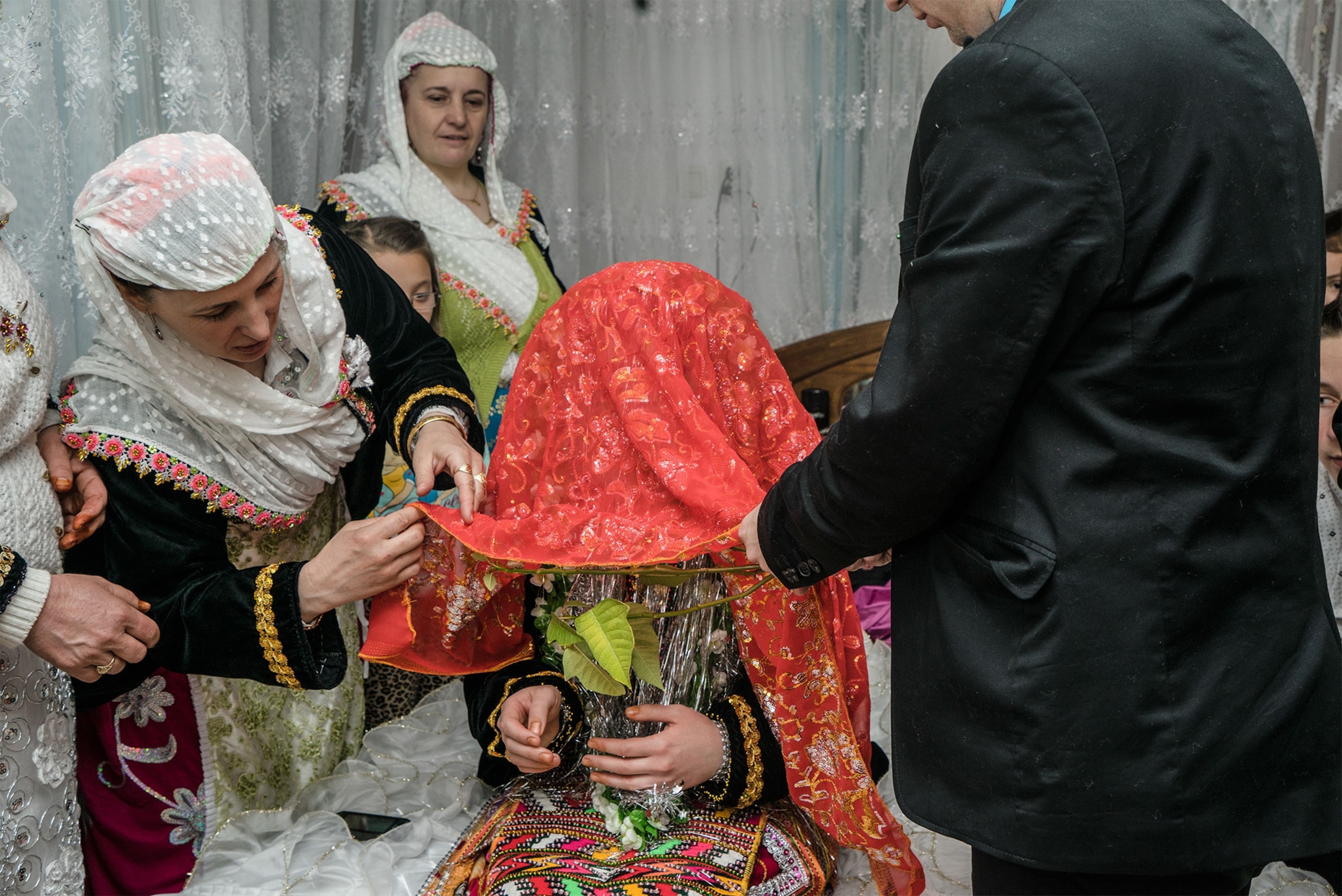 the groom's family lifting the veil of a bride in a ceremony
