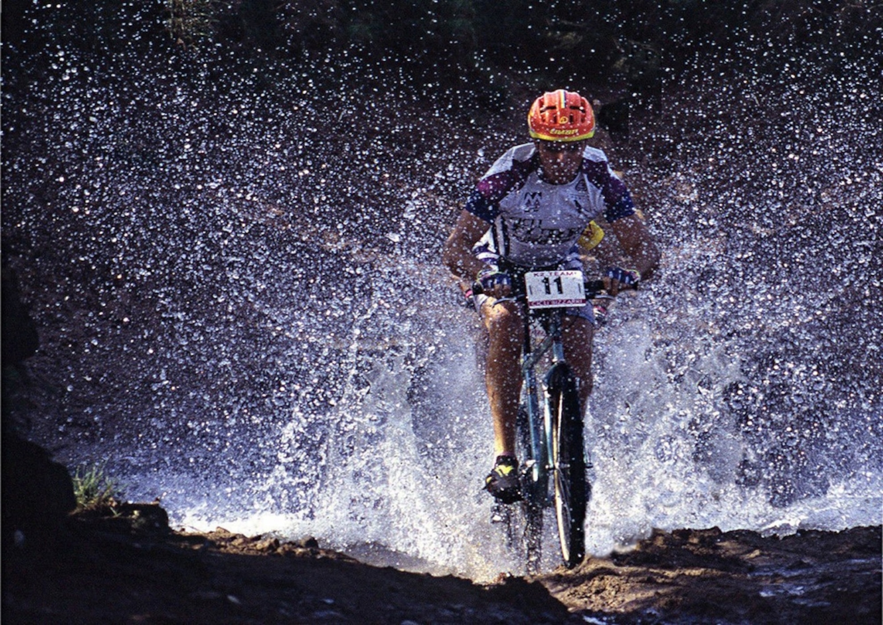 Mountain bike racer splashes through a puddle.