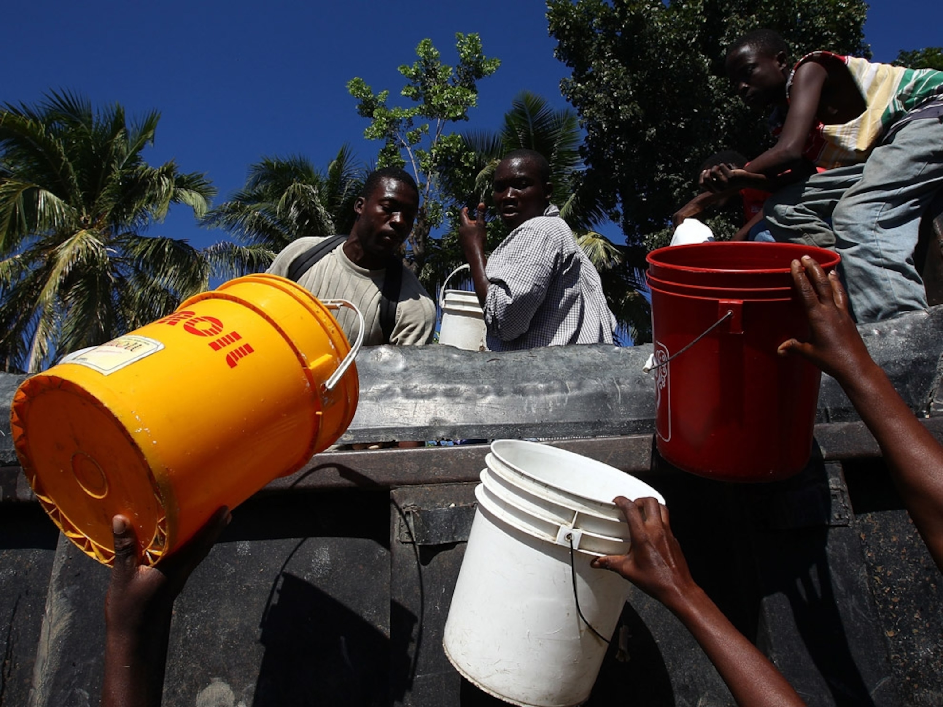Workers distribute water to people with buckets