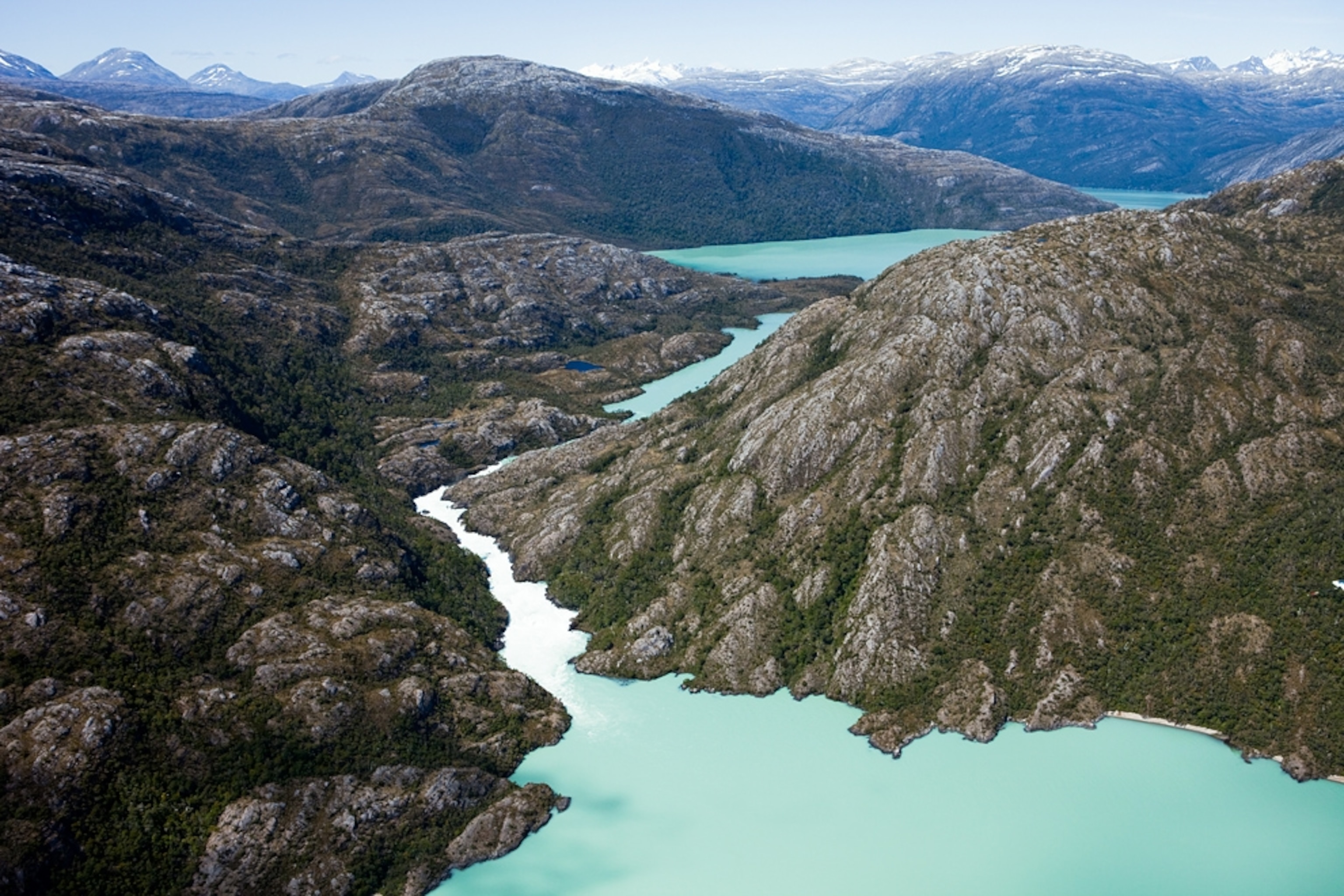 A river springs from a lake in a rocky, mountainous landscape