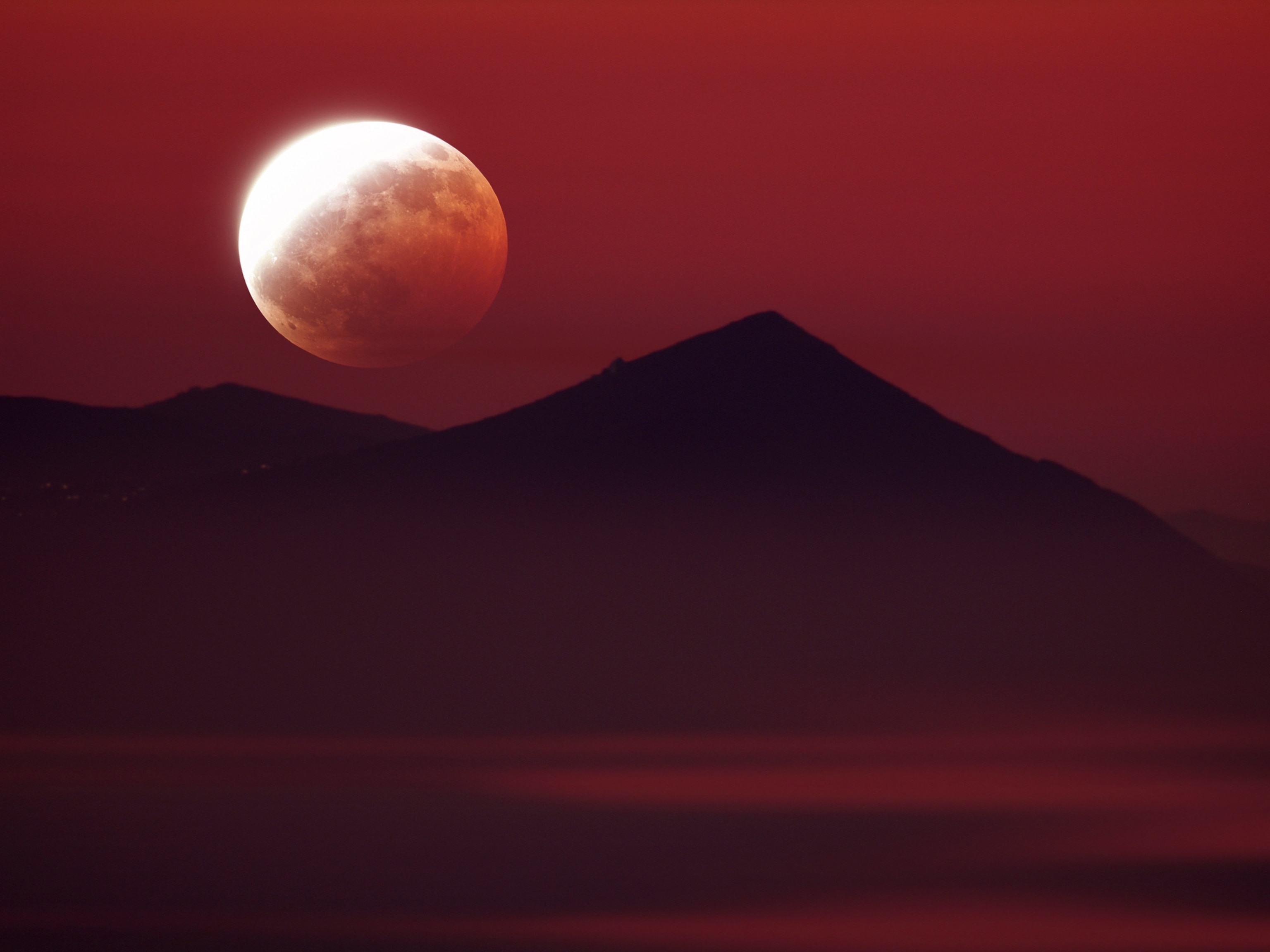 A partial lunar eclipse above Greek mountains.