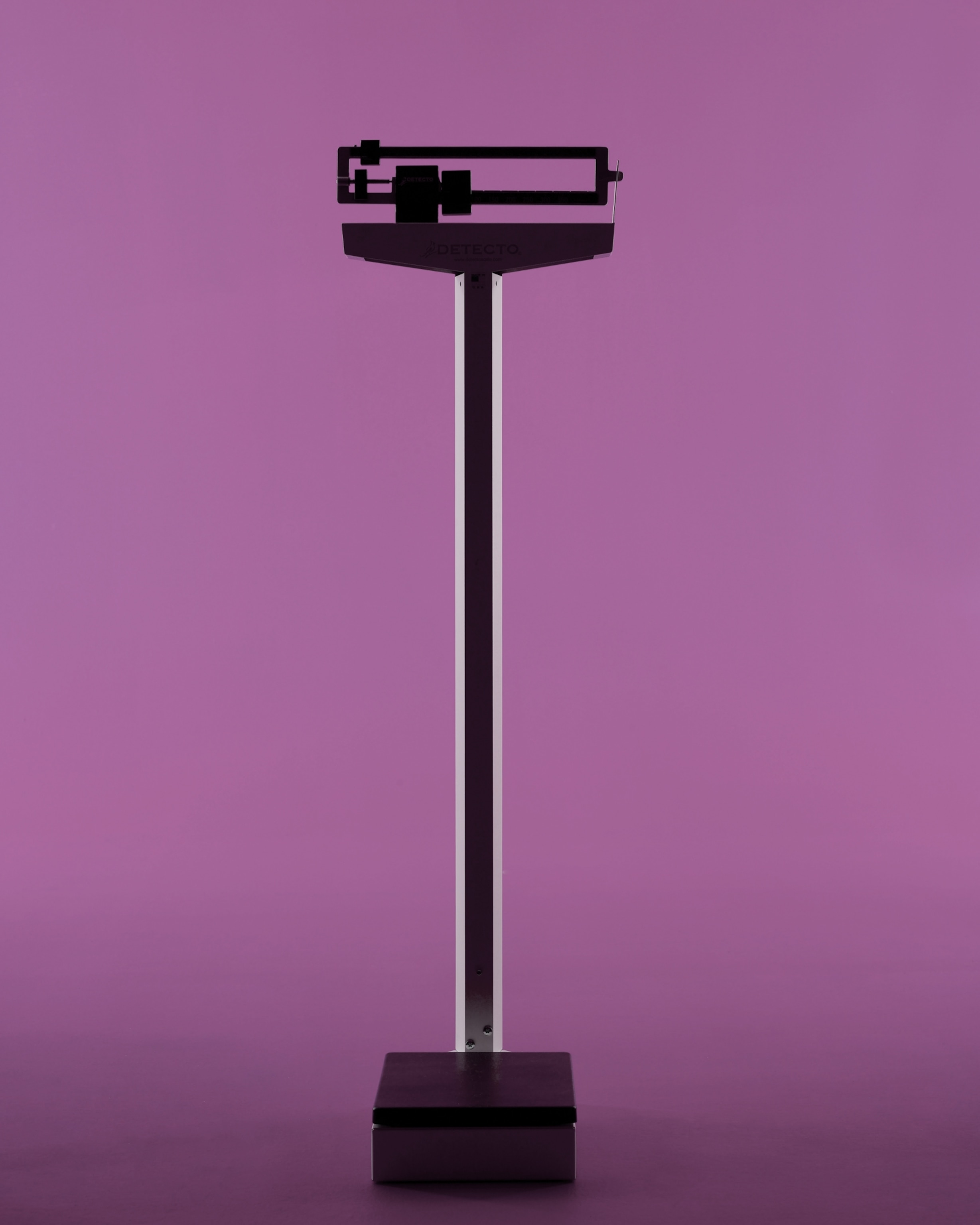 A mechanical scale stands alone against a vibrant purple backdrop.