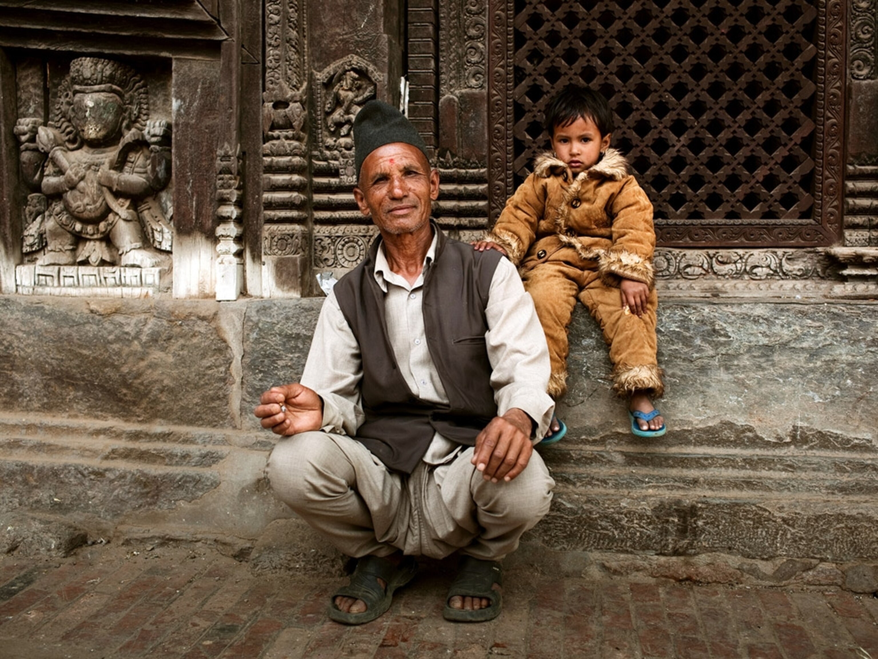 A man and a little girl sitting in front of a temple