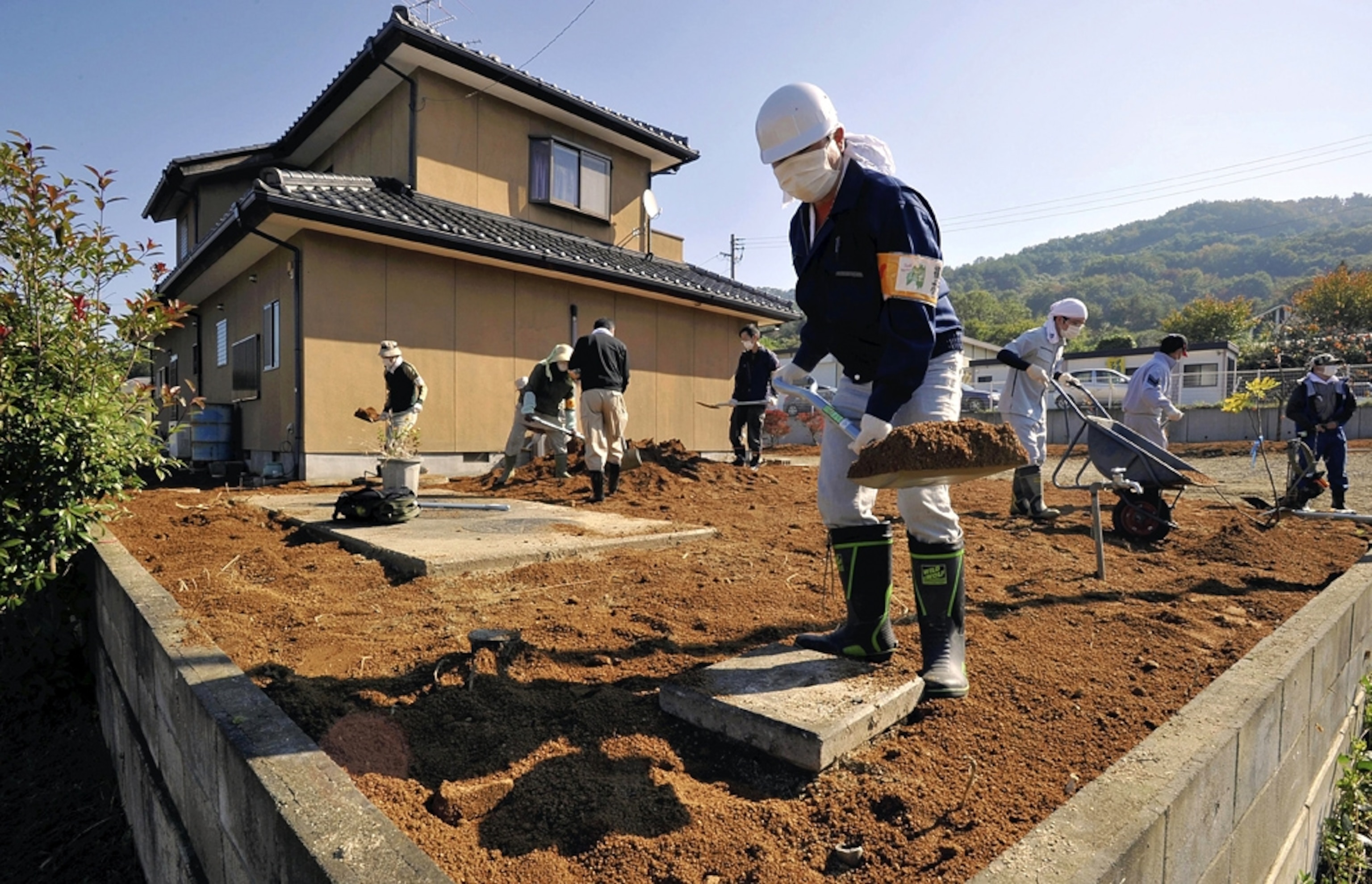 Workers decontaminate the garden of a house in Fukushima