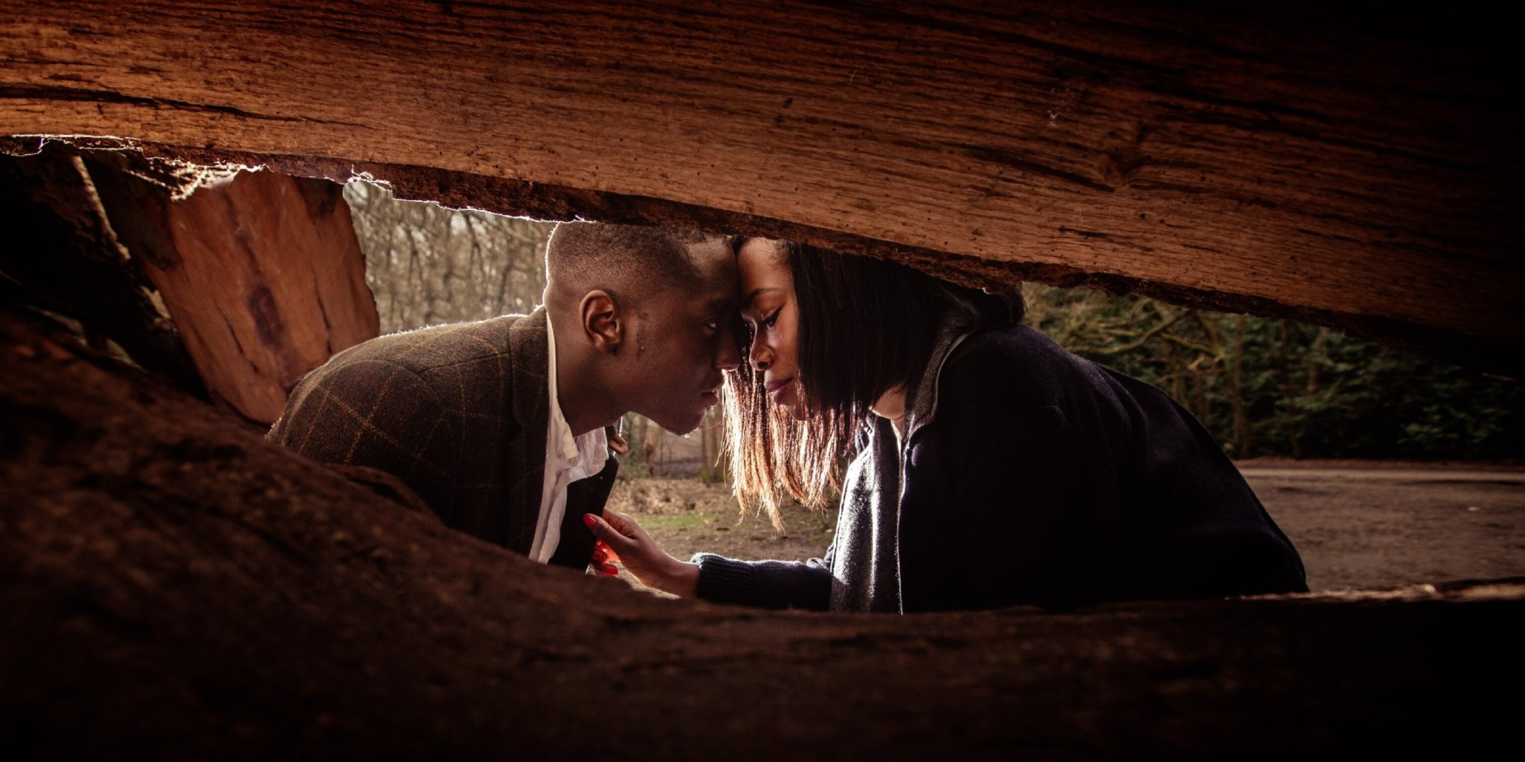 a couple getting engaged behind a tree