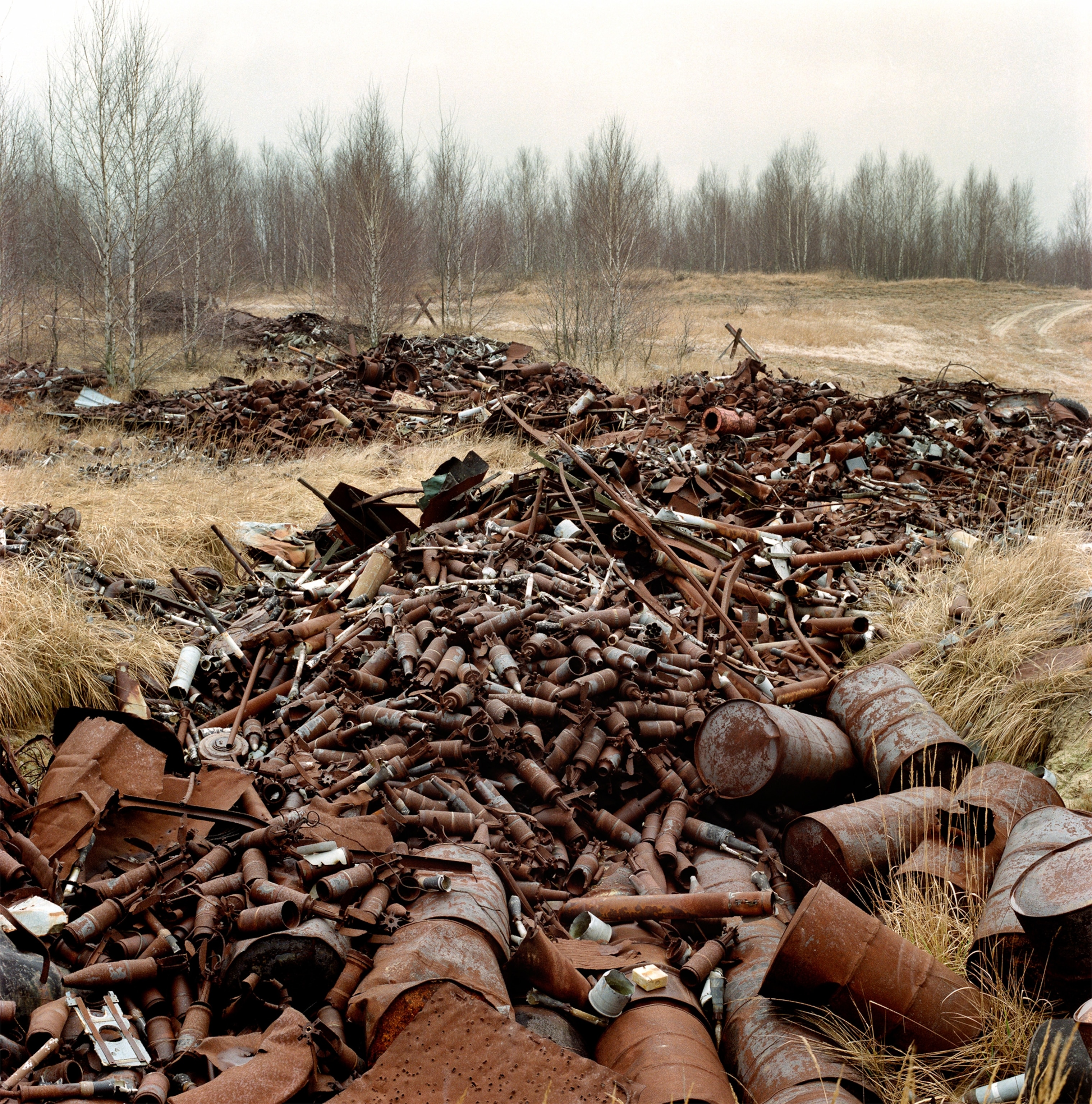 discarded and rusting ammunition canisters piled up in a former exercise terrain of the Soviet army.