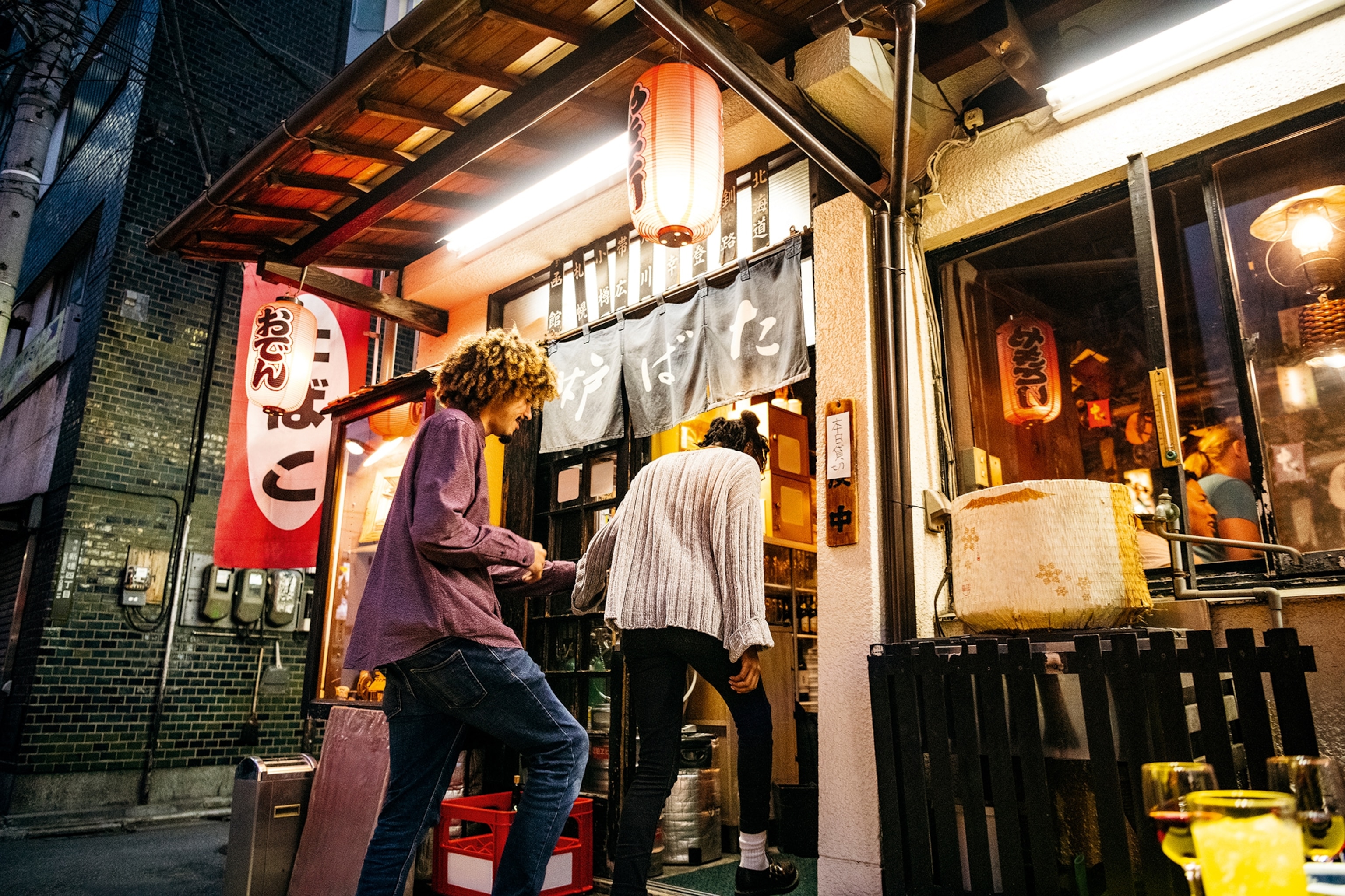 Two travellers heading into an izakaya bar-restaurant in Japan.