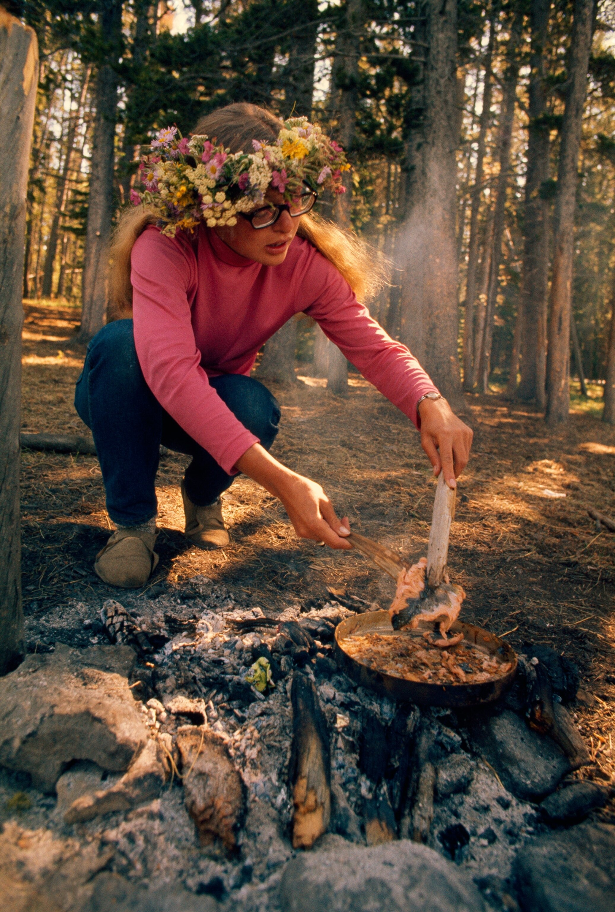 a woman cooking over campfire