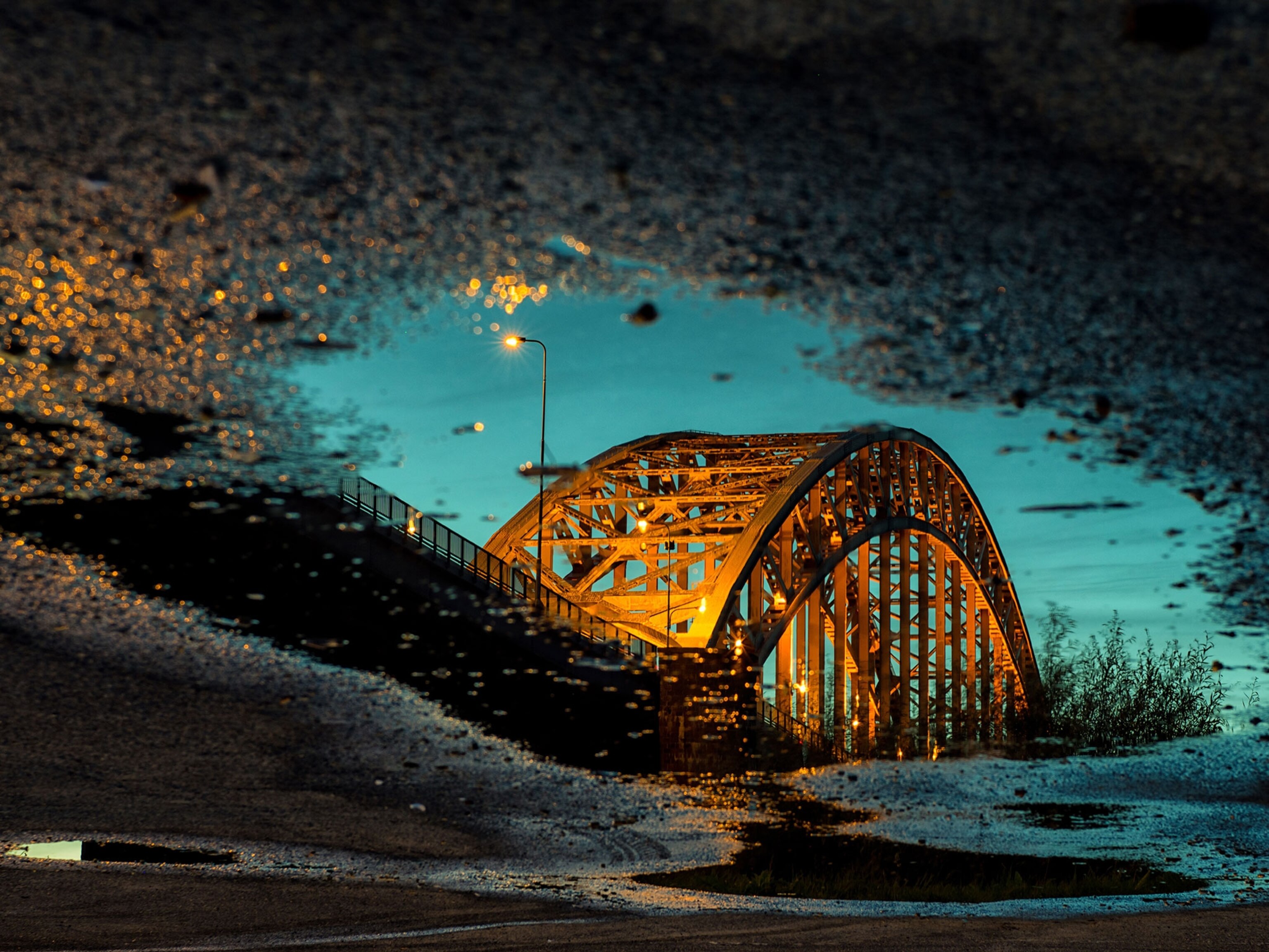 a yellow bridge reflected in a blue puddle