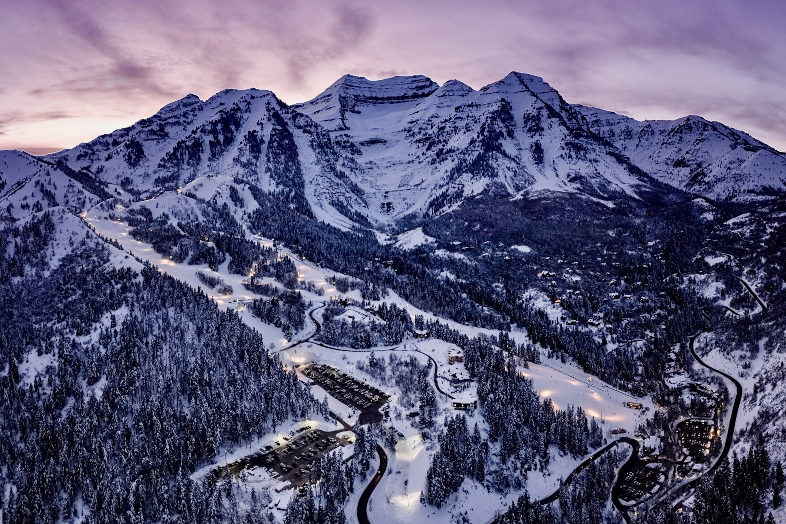 A mountain valley at dusk with slopes snaking down the main, central peak.