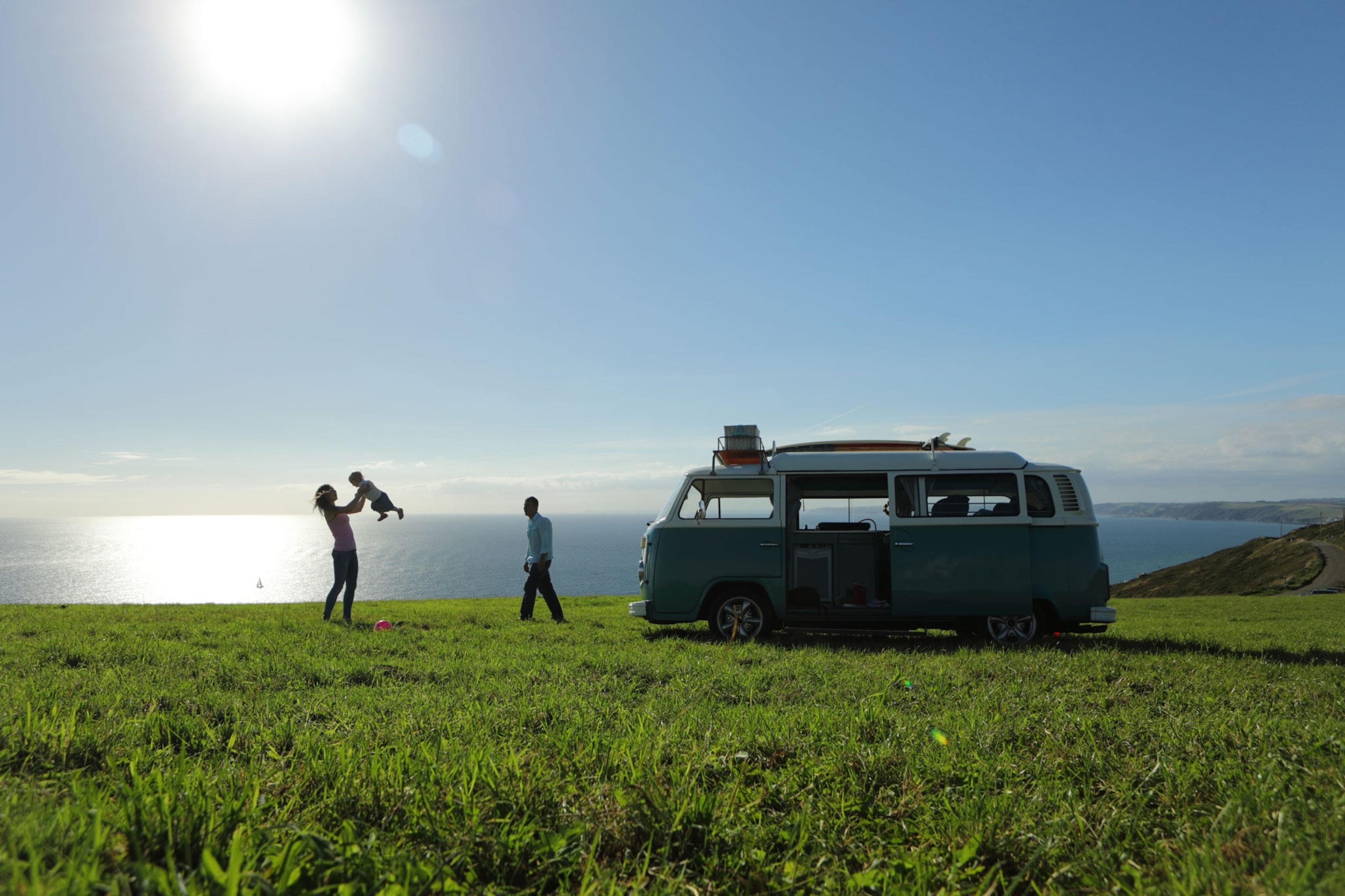 A family next to their camper van with a scenic coastal backdrop