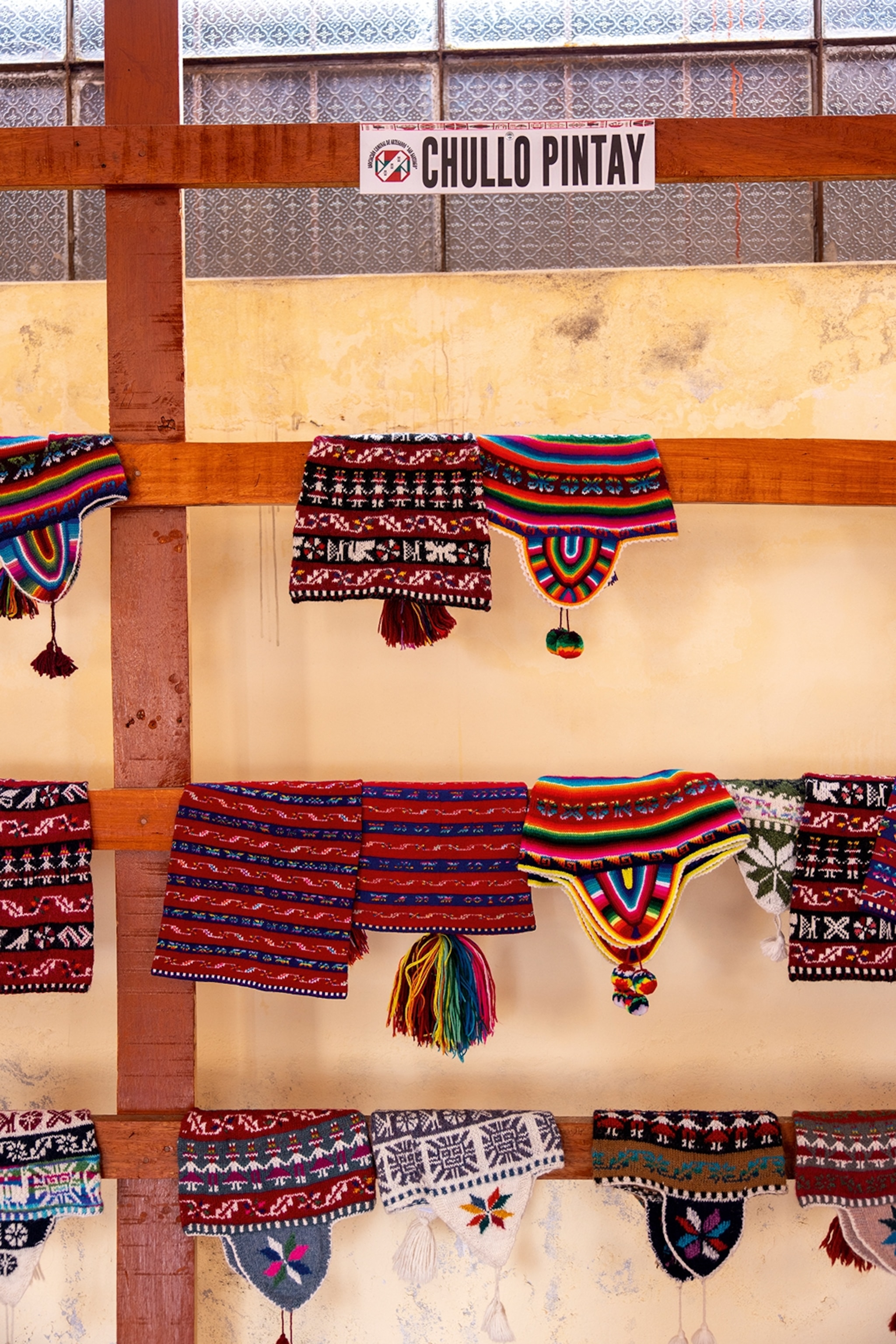 A selection of woven hats hung over wooden rails.