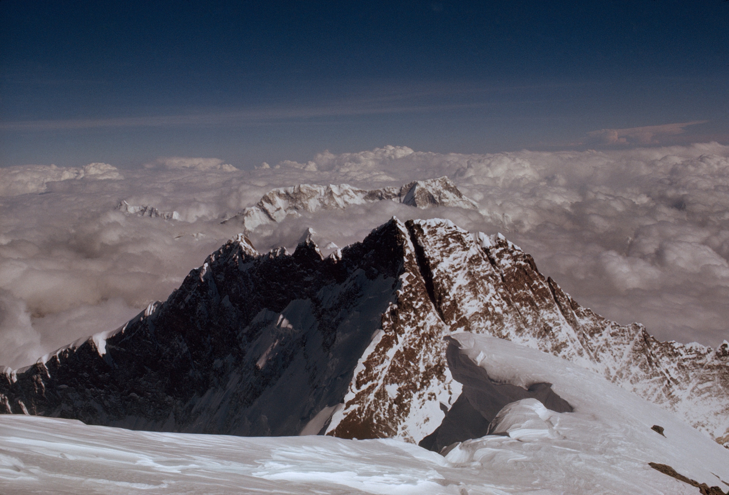Viewed from Earth’s highest point, distant Kanchenjunga (left) and nearby Makalu burst through clouds; House forms the dark mass at right. The panorama combines two pictures taken during the 45 minutes that Jerstad and Bishop spent at the summit.