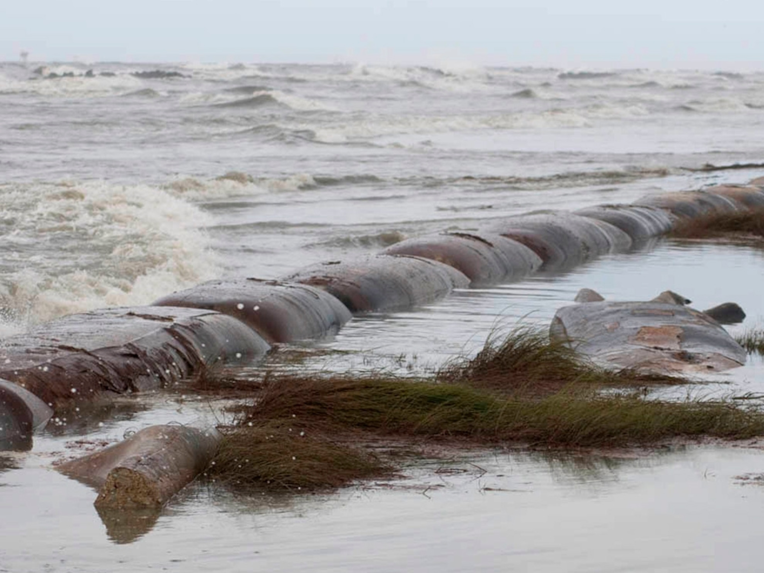 waves crashing on concrete barricades along a Port Fourchon, Louisiana, beach.