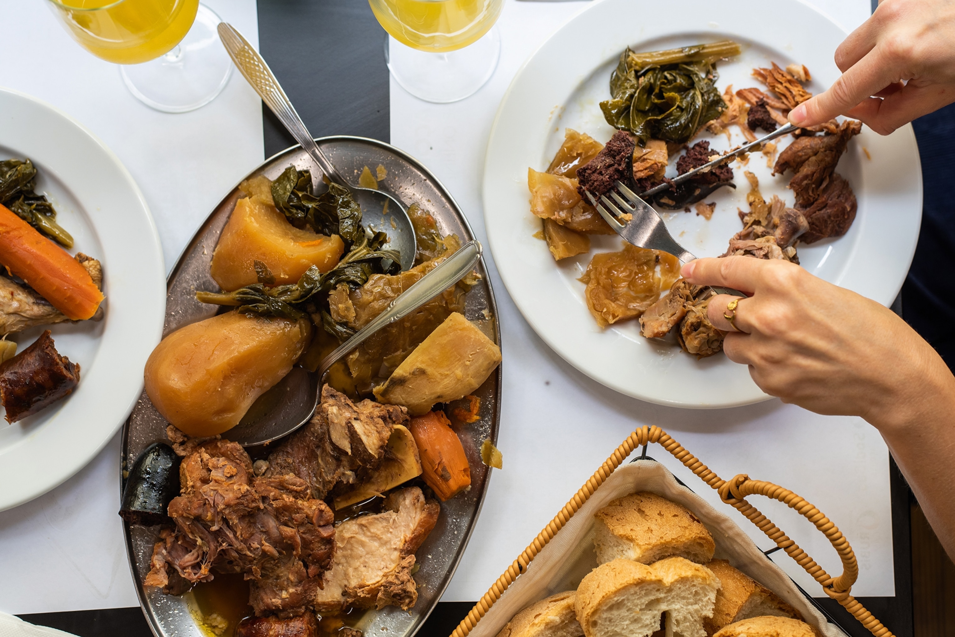 A lavish spread of meat-forward dishes as someone tucks into the food with a knife and fork.