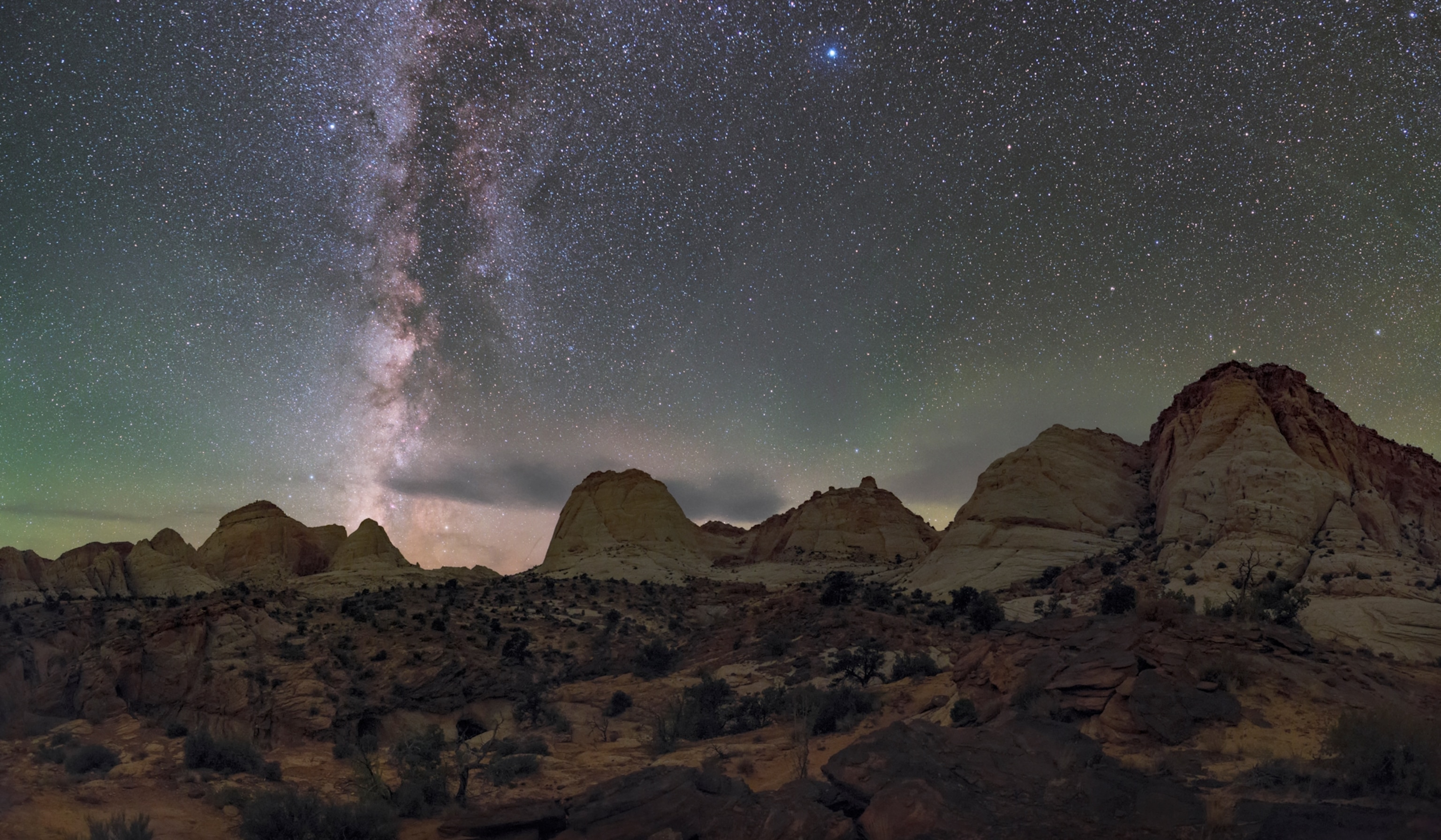 Milky Way above the Capitol Reef National Park with Navajo Sandstone dome formations.