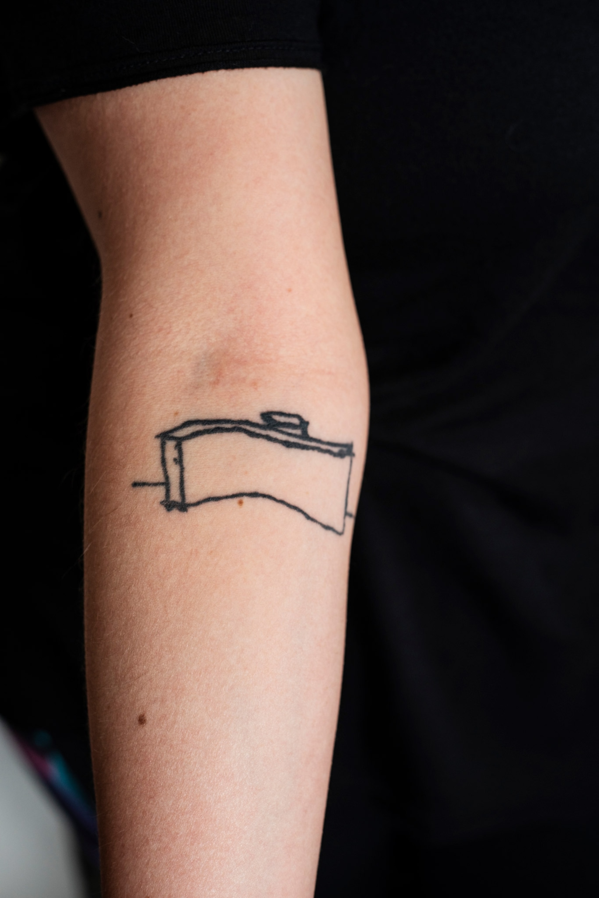 a woman's forearm with a simple line tattoo