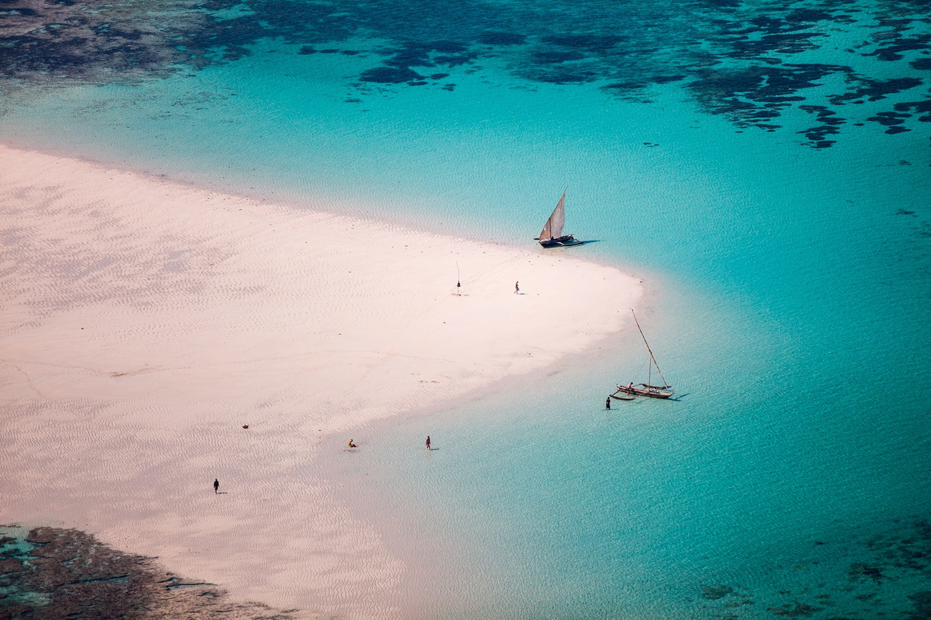 An aerial shot of a quiet coast line with long stretches of sand reaching into the ocean.
