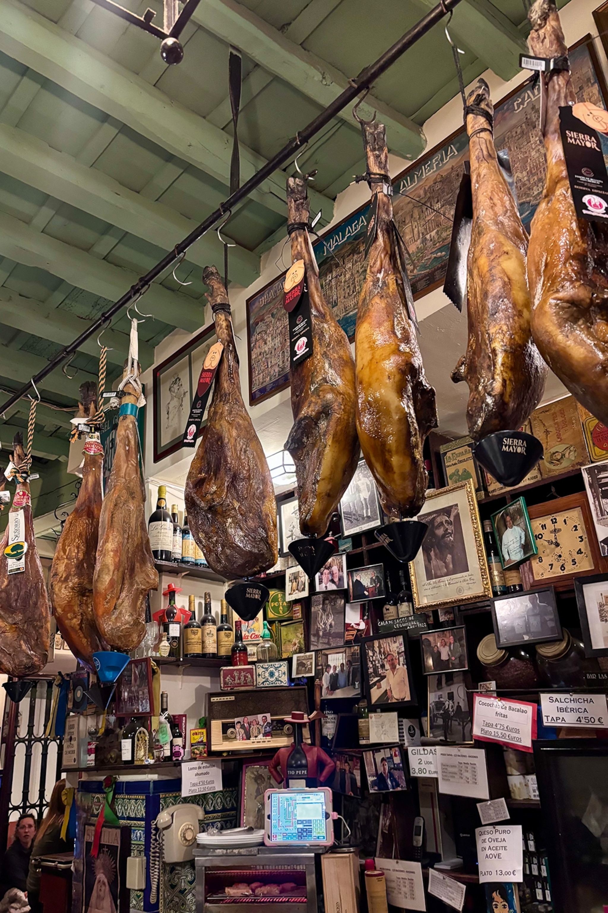 A shop hung with countless picture frames and a rail of iberico ham legs curing below the wood-beamed ceiling.
