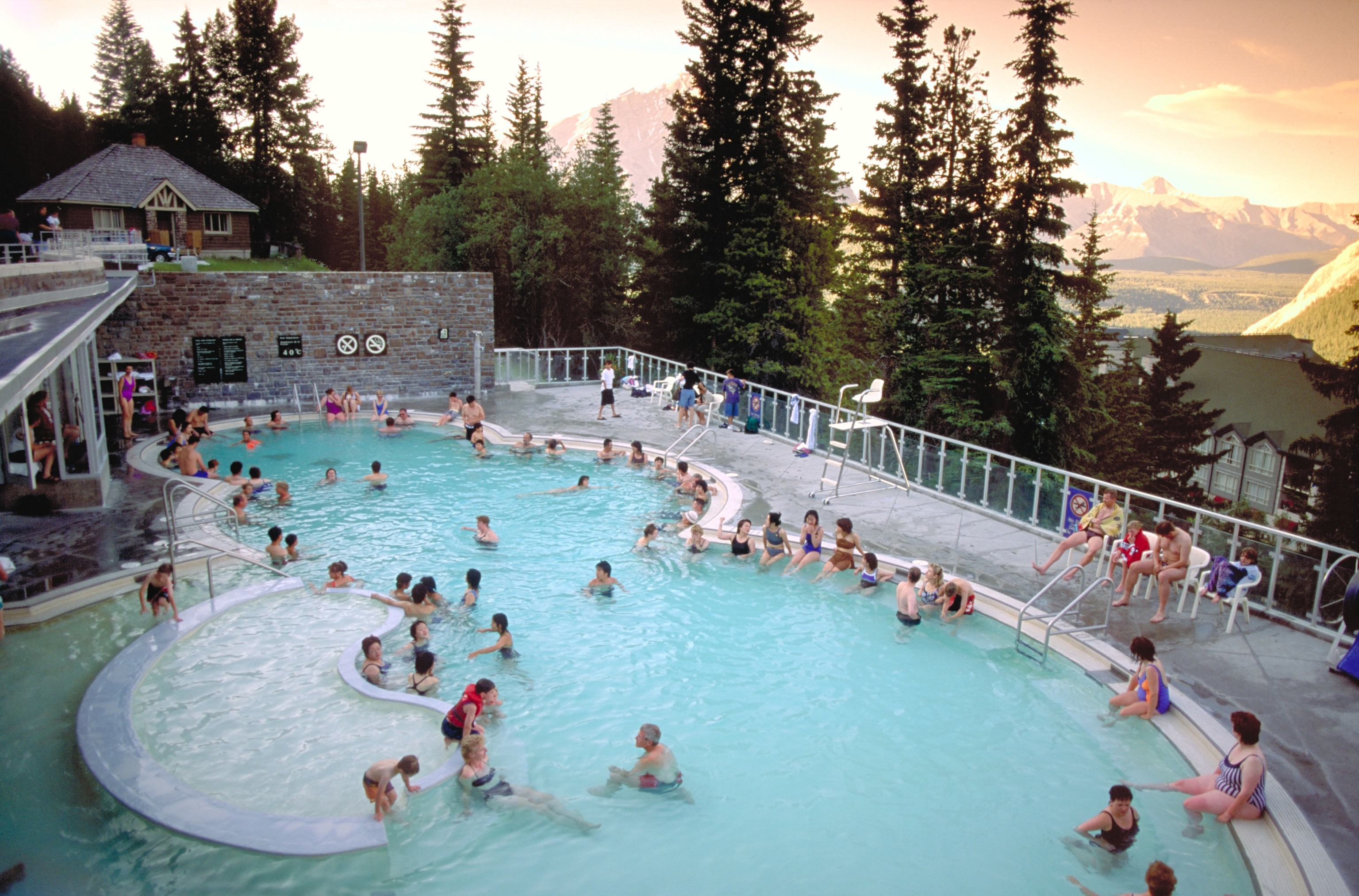 People in an outdoor swimming pool with a view of mountains.