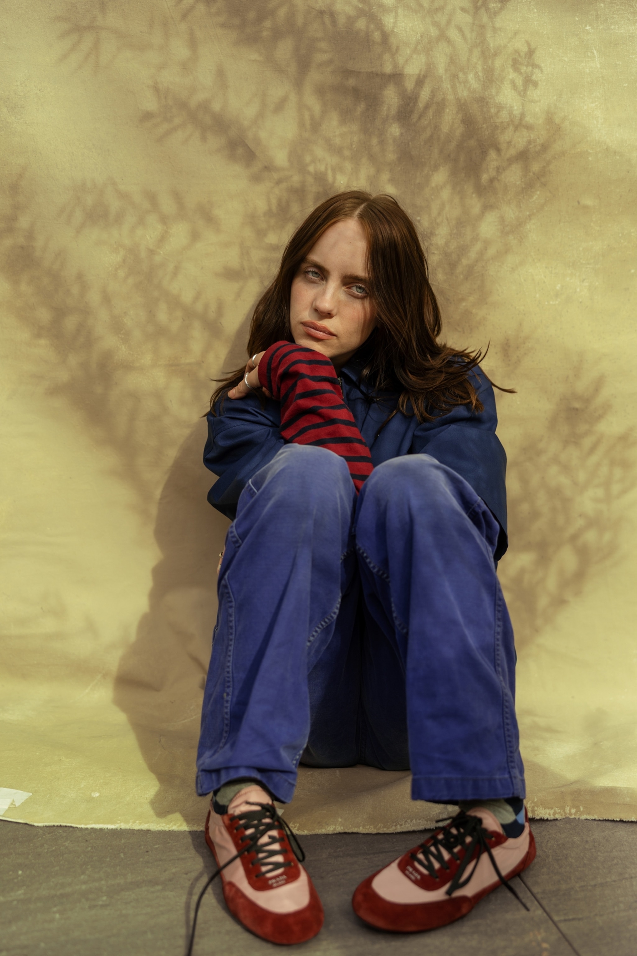 portrait of a woman with dark long hair sitting on the ground with her knees up