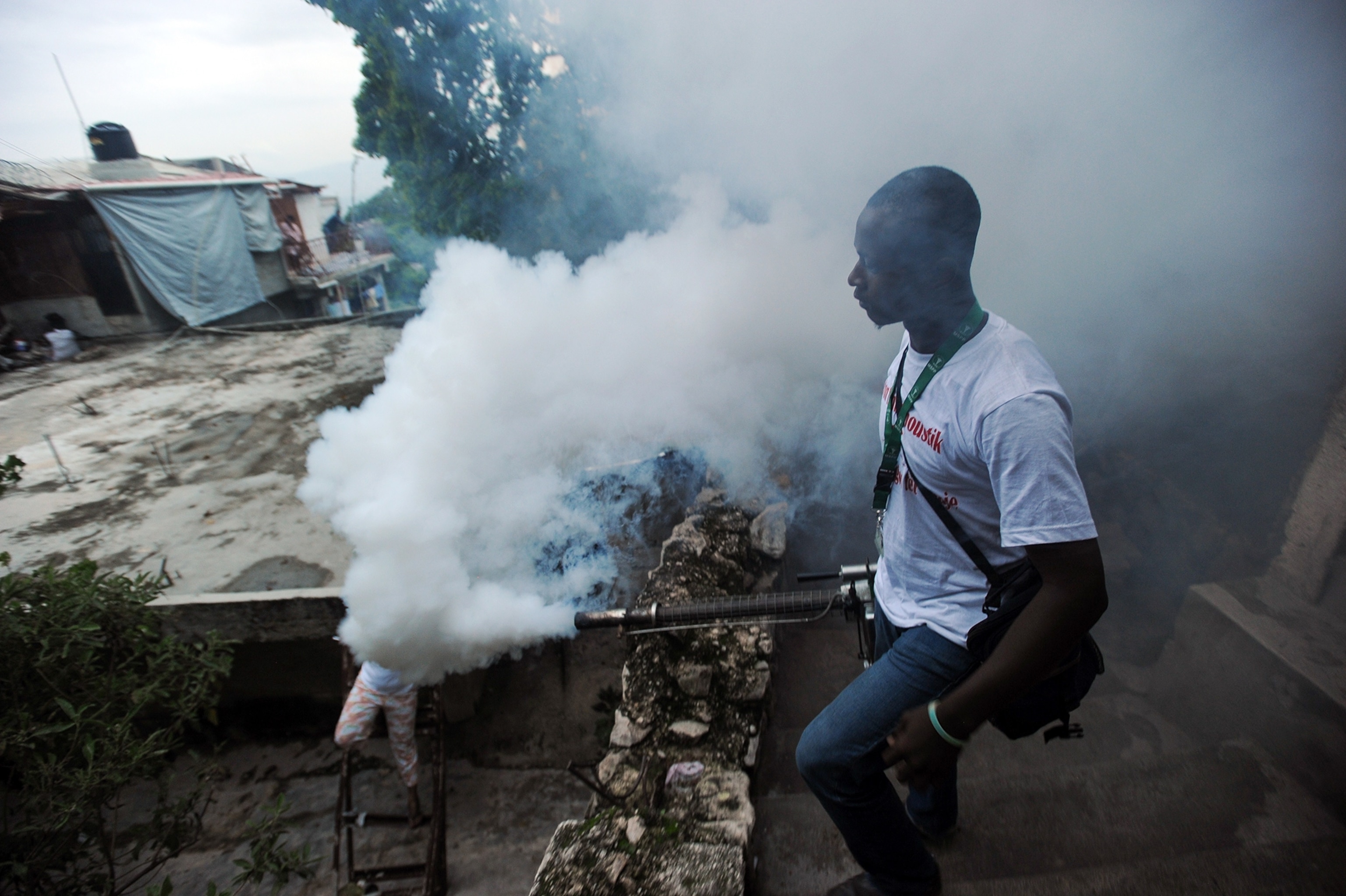 a worker from Haiti's Ministry of Public Health spraying chemicals to exterminate mosquitos to prevent the Chikungunya virus.