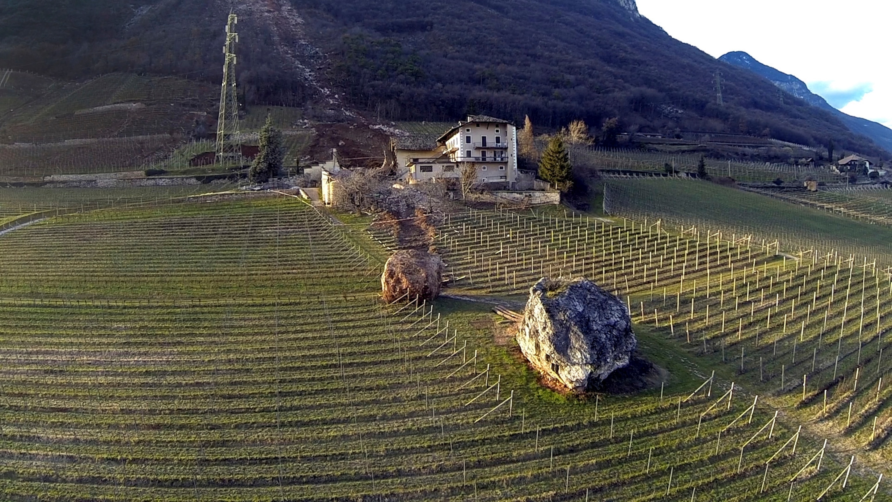 In this photo provided by Tareom.com Thursday, Jan. 30, 2014, and taken on Jan. 23, 2014, a huge boulder is seen after it missed a farm house by less than a meter, destroying the barn, and stopped in the vineyard, while a second giant boulder, which detached during the same landslide on Jan. 21, 2014, stopped next to the house, in Ronchi di Termeno, in Northern Italy.