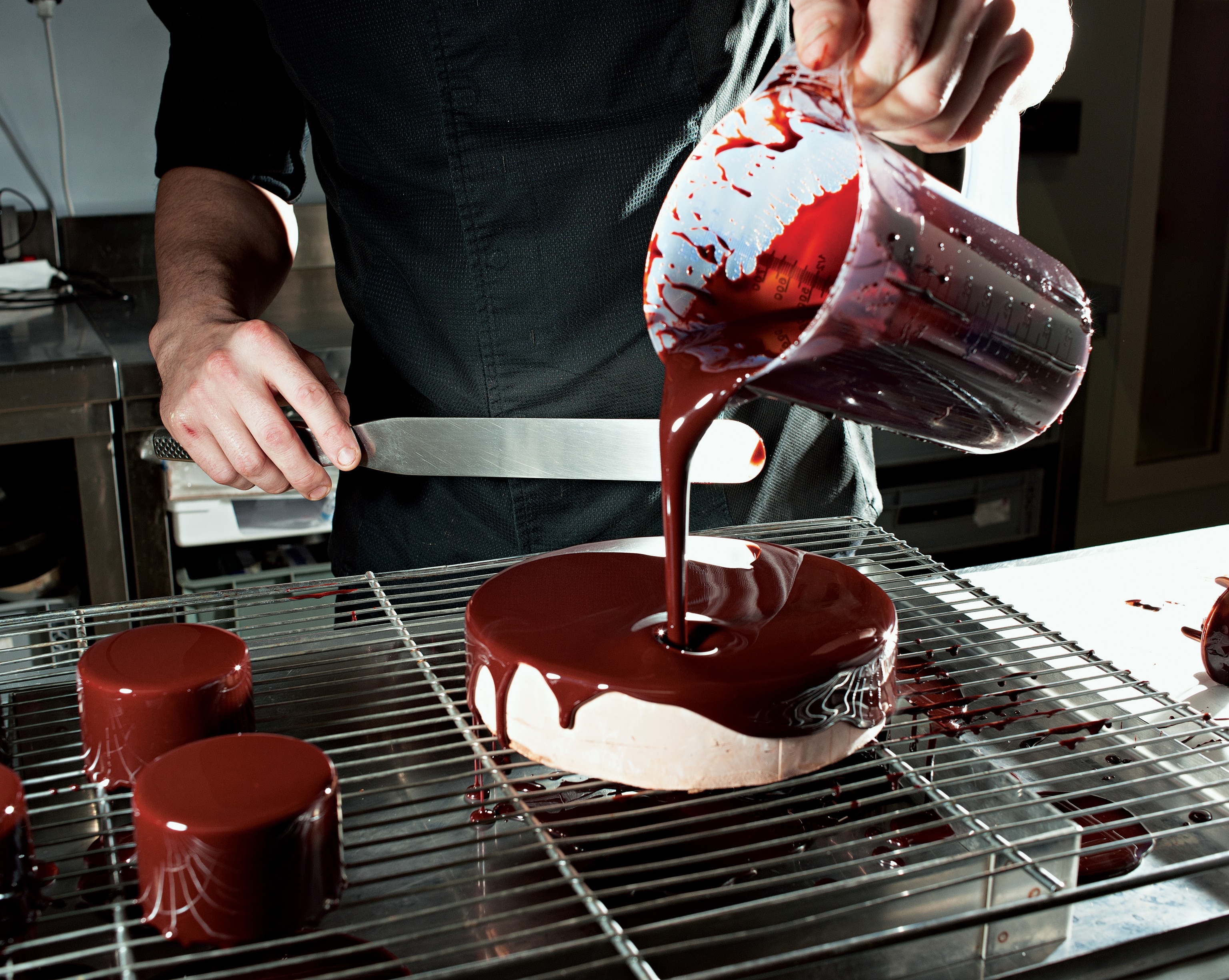 chocolate glaze pouring from a pitcher to coat a cake at Maison Pariès in Bayonne, France