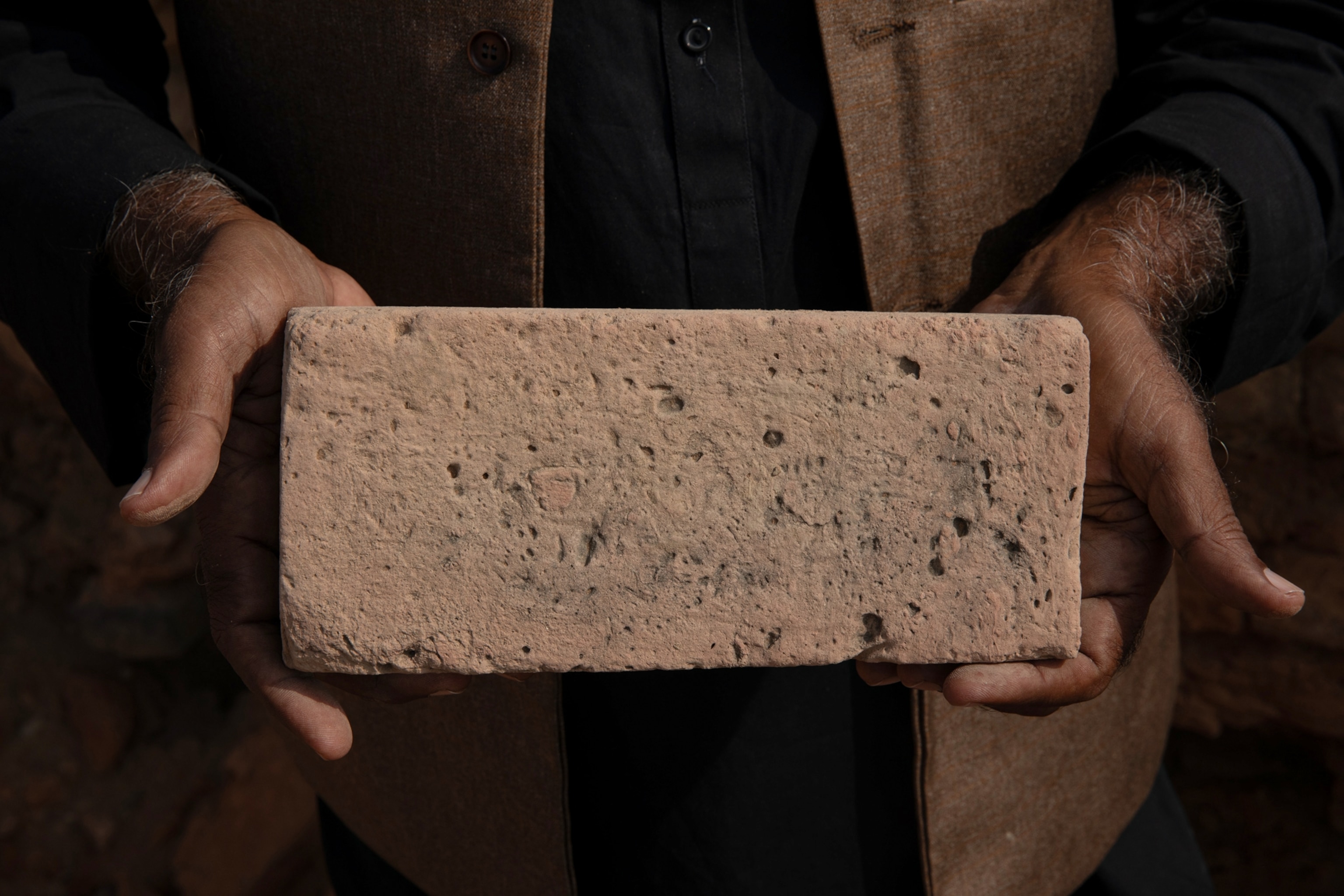 Two hands hold a brick